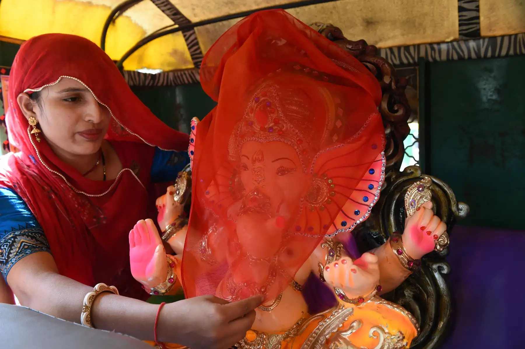 Un devoto hindú cubre la cara de un ídolo del señor hindú Ganesha con cabeza de elefante. Foto: AFP