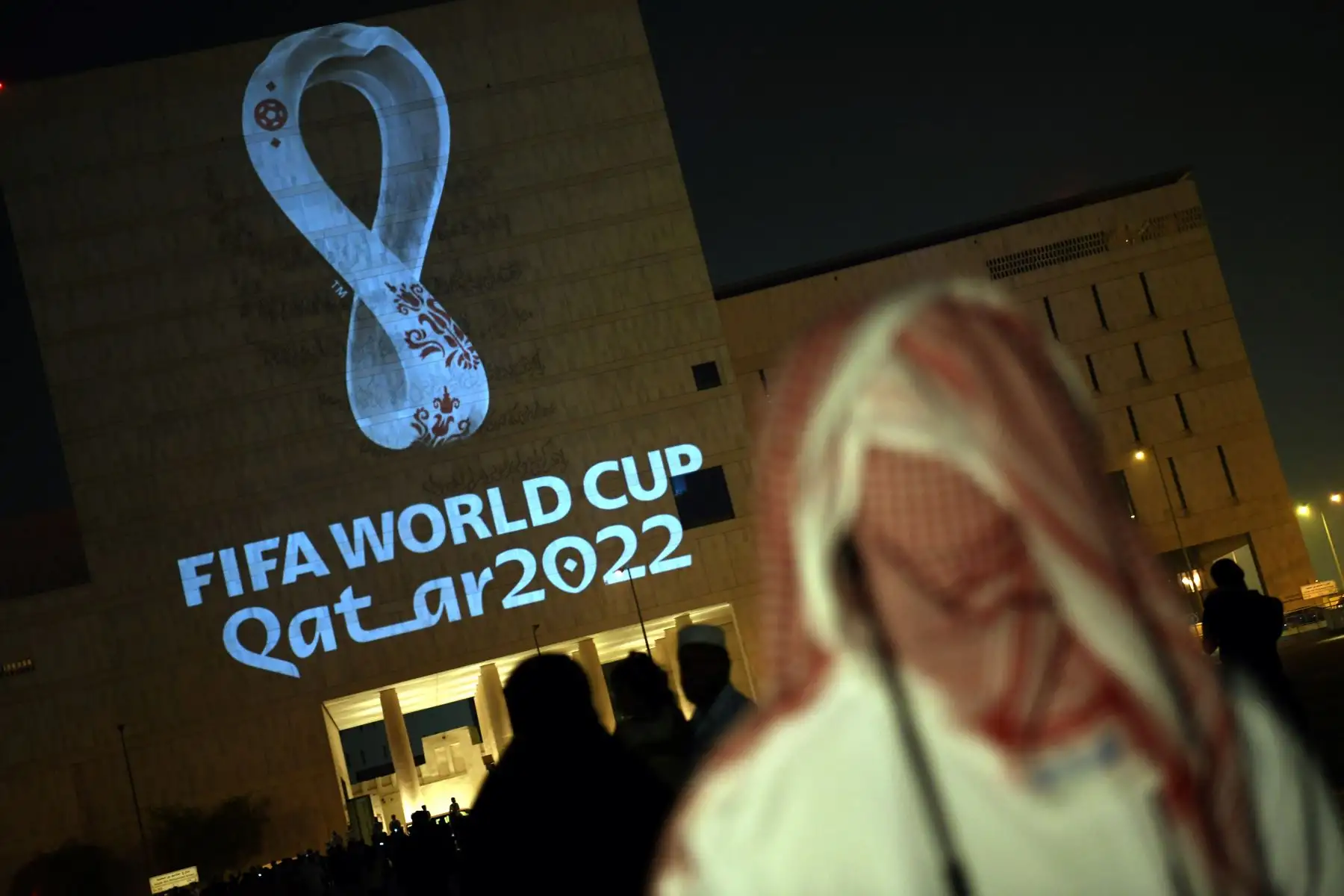 Los qataríes se reúnen en el mercado tradicional Souq Waqif de Doha, la capital, mientras el logotipo oficial de la Copa Mundial de la FIFA Qatar 2022 se proyecta en el frente de un edificio. Foto:AFP