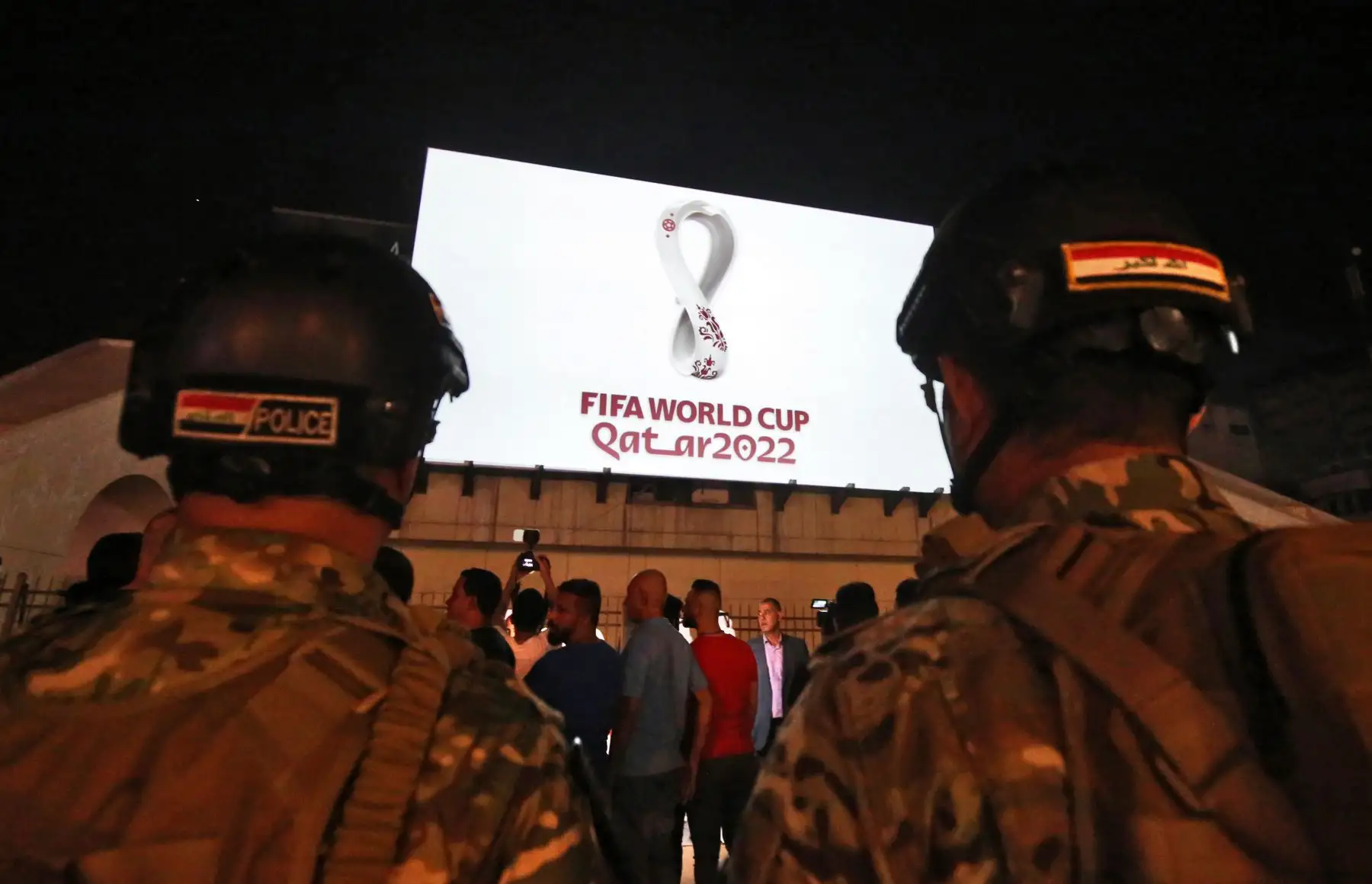 Los iraquíes se reúnen en la plaza Tahir de Bagdad mientras el logotipo oficial de la Copa Mundial de la FIFA Qatar 2022 se proyecta en el frente de un edificio. Foto.AFP