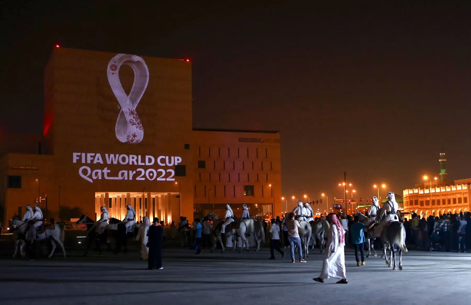 Los qataríes se reúnen en el mercado tradicional Souq Waqif de Doha, la capital, mientras el logotipo oficial de la Copa Mundial de la FIFA Qatar 2022 se proyecta en el frente de un edificio.Foto:AFP