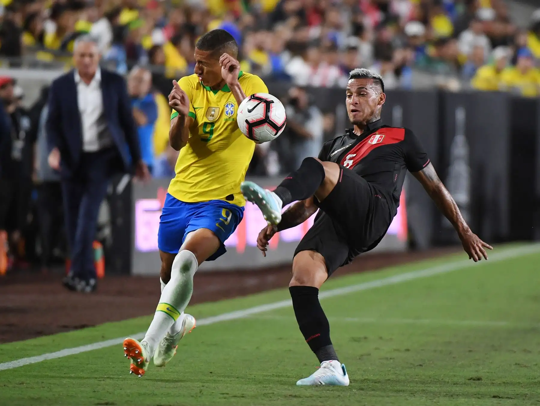 Richarlison de Brasil (L) es abordado por Miguel Trauco de Perú (R) durante el partido amistoso de fútbol internacional entre Brasil y Perú en el Los Angeles Memorial Coliseum, en Los Ángeles, California, el 10 de septiembre de 2019. Foto: AFP