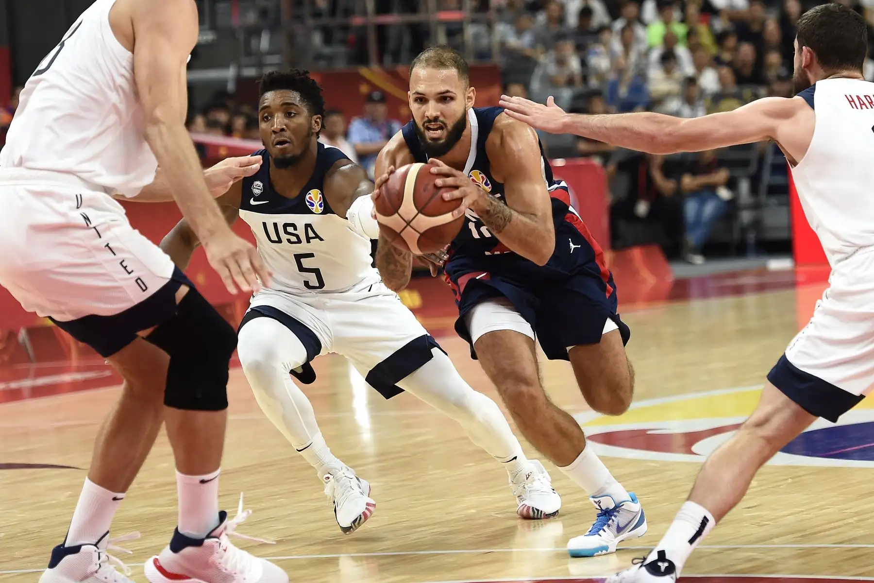 El francés Evan Fournier (C) corre con el balón junto a Donovan Mitchell de los Estados Unidos. Foto: AFP