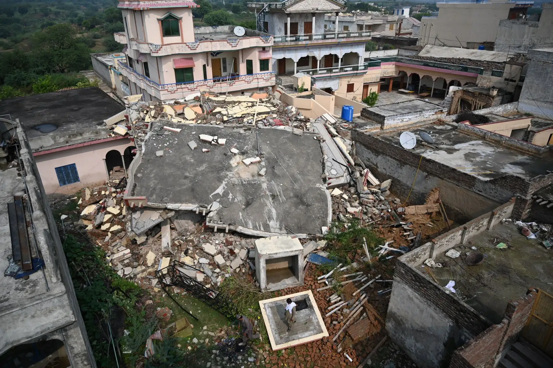 Residentes paquistaníes miran una casa derrumbada en un área afectada por un terremoto en las afueras de Mirpur en Pakistán. Foto: AFP