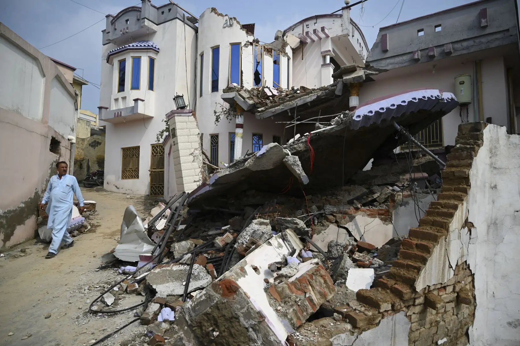 Residentes paquistaníes miran una casa derrumbada en un área afectada por un terremoto en las afueras de Mirpur en Pakistán. Foto: AFP