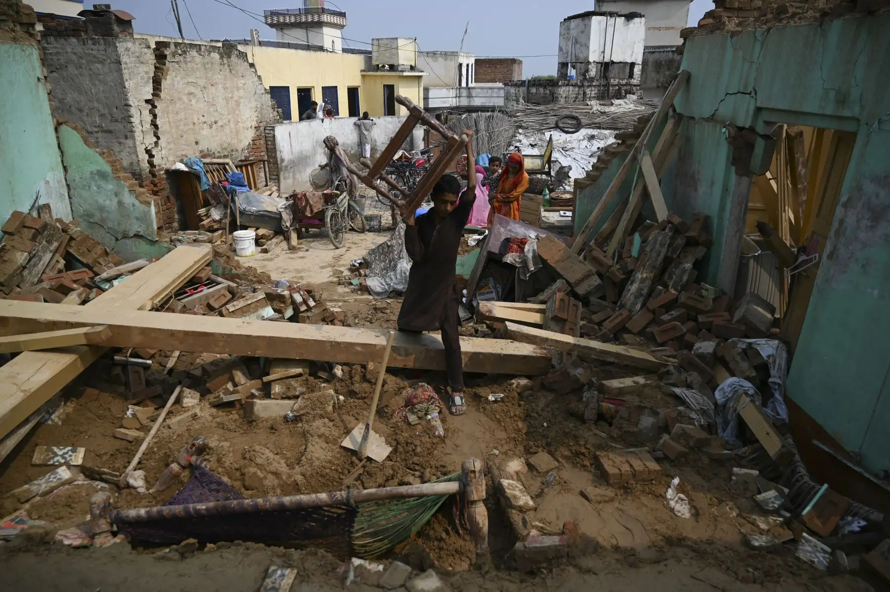 Un sobreviviente del terremoto mueve sus pertenencias entre los escombros de las casas derrumbadas en las afueras de Mirpur en Pakistán. Foto: AFP