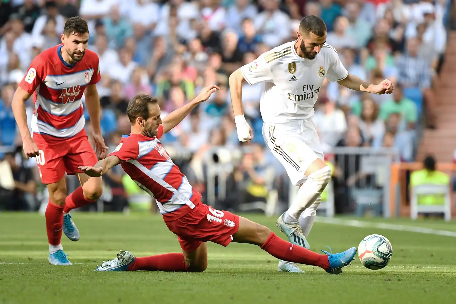 El defensor español de Granada Víctor Díaz intercepta al delantero francés del Real Madrid Karim Benzema en el Santiago Benabéu. Foto: AFP