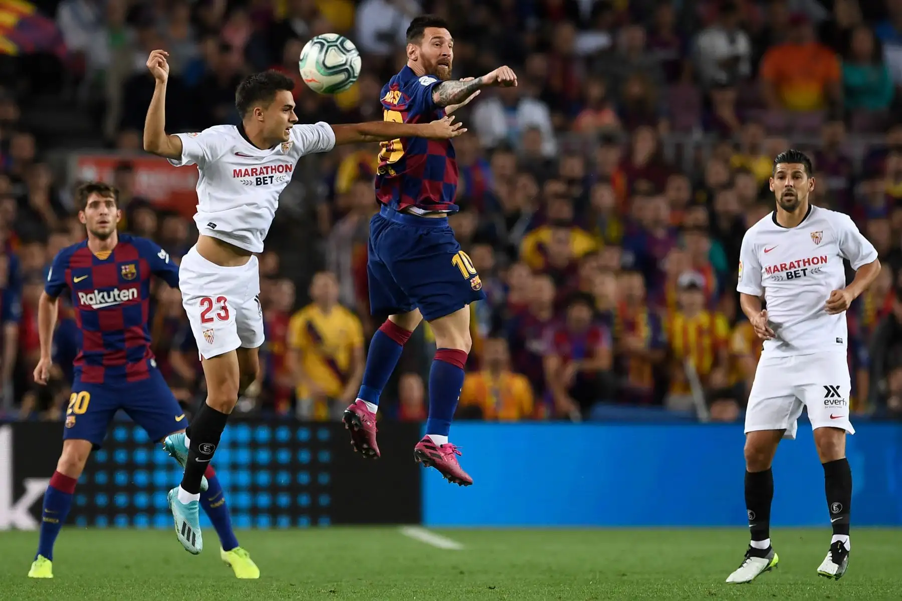 El defensa español de Sevilla Sergio Reguilon compite un balón aéreo contra el astro argentino de Barcelona Lionel Messi. Foto: AFP