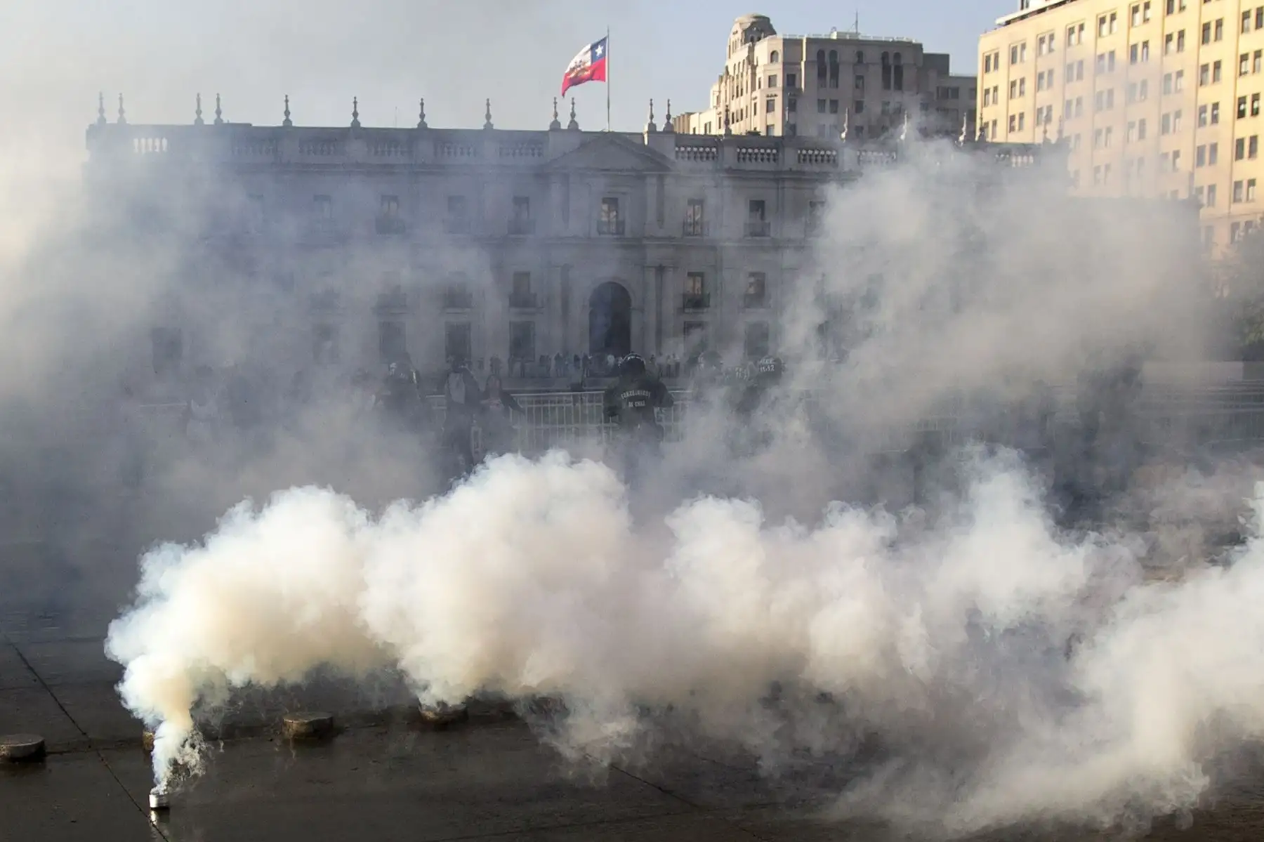 Los manifestantes se enfrentan con la policía antidisturbios después de una protesta masiva de evasión de tarifas frente al palacio de La Moneda, Santiago. AFP