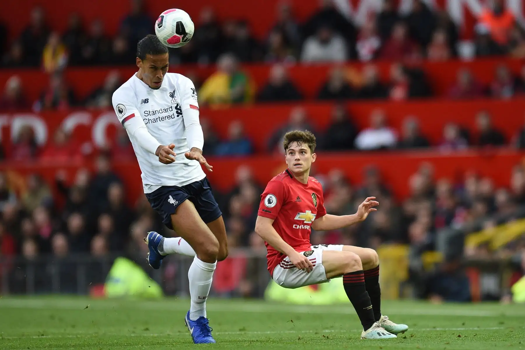 El defensor holandés del Liverpool Virgil van Dijk controla el balón con la cabeza ante marca del  centrocampista galés del Manchester United Daniel James en partido de Premier League. Foto: AFP