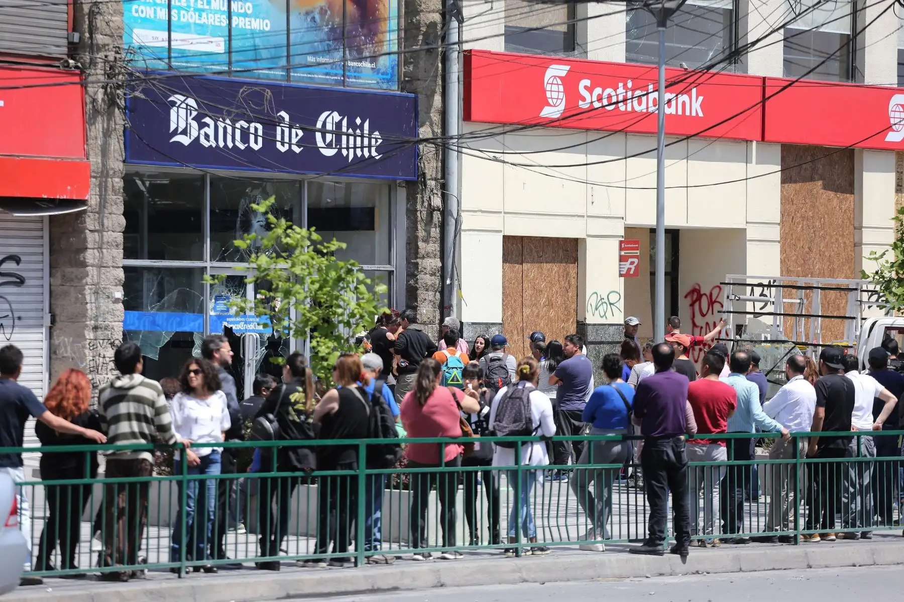 Ciudadanos hacen largas fila en os cajeros automáticos que lucen destruídos por enfrentamientos, en Santiago. Foto: EFE