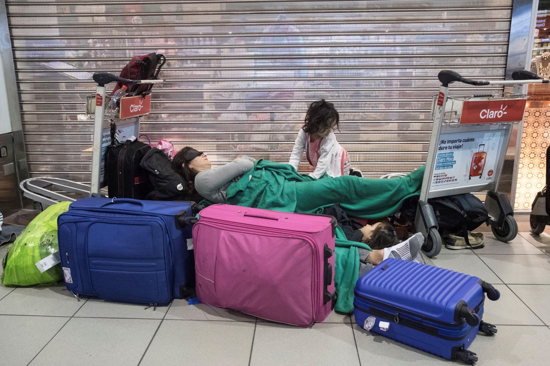 Una mujer descansa junto a su hija mientras cientos de pasajeros quedaron en la noche de este domingo y la madrugada del lunes atrapados en el aeropuerto de Santiago de Chile. Foto: EFE