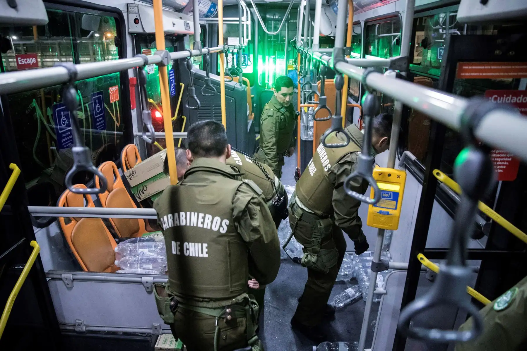 Efectivos de Carabineros ayudan en la entrega de alimentos y agua a los cientos de pasajeros que quedaron en la noche de este domingo y la madrugada del lunes atrapados en el aeropuerto tras la cancelación de sus vuelos debido al toque de queda. Foto: EFE