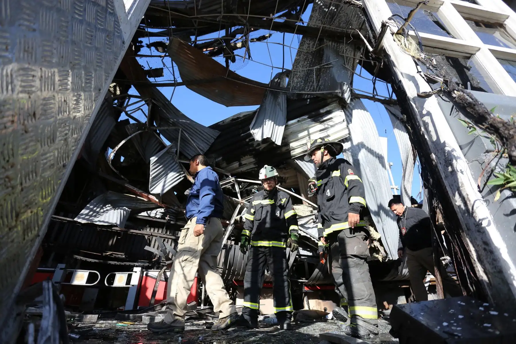 Personal policial y bomberos inspeccionan un supermercado después de ser saqueado e incendiado por manifestantes, en medio de la coyuntura de protestas en Santiago. Foto: EFE