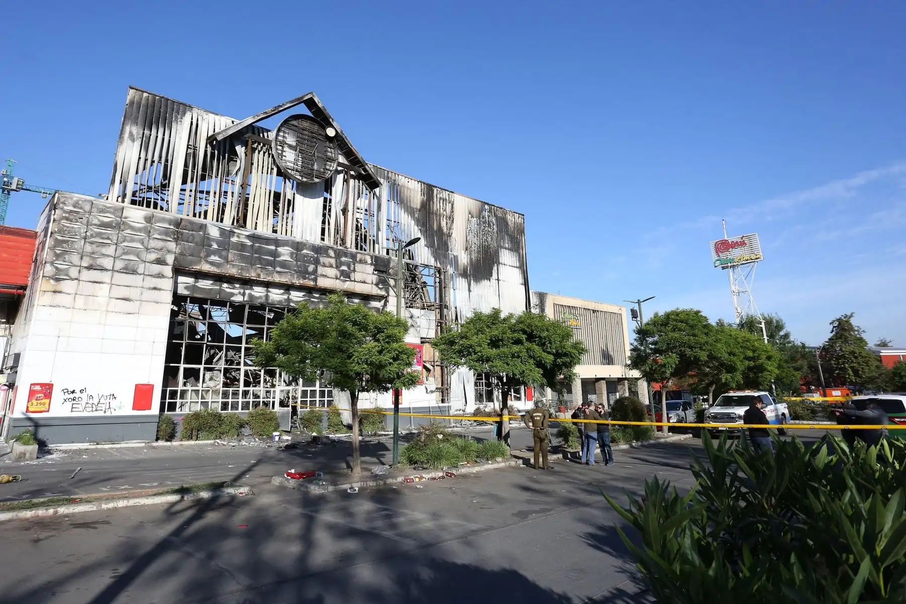 Personal policial y bomberos inspeccionan un supermercado después de ser saqueado e incendiado por manifestantes, en medio de la coyuntura de protestas en Santiago. Foto: EFE