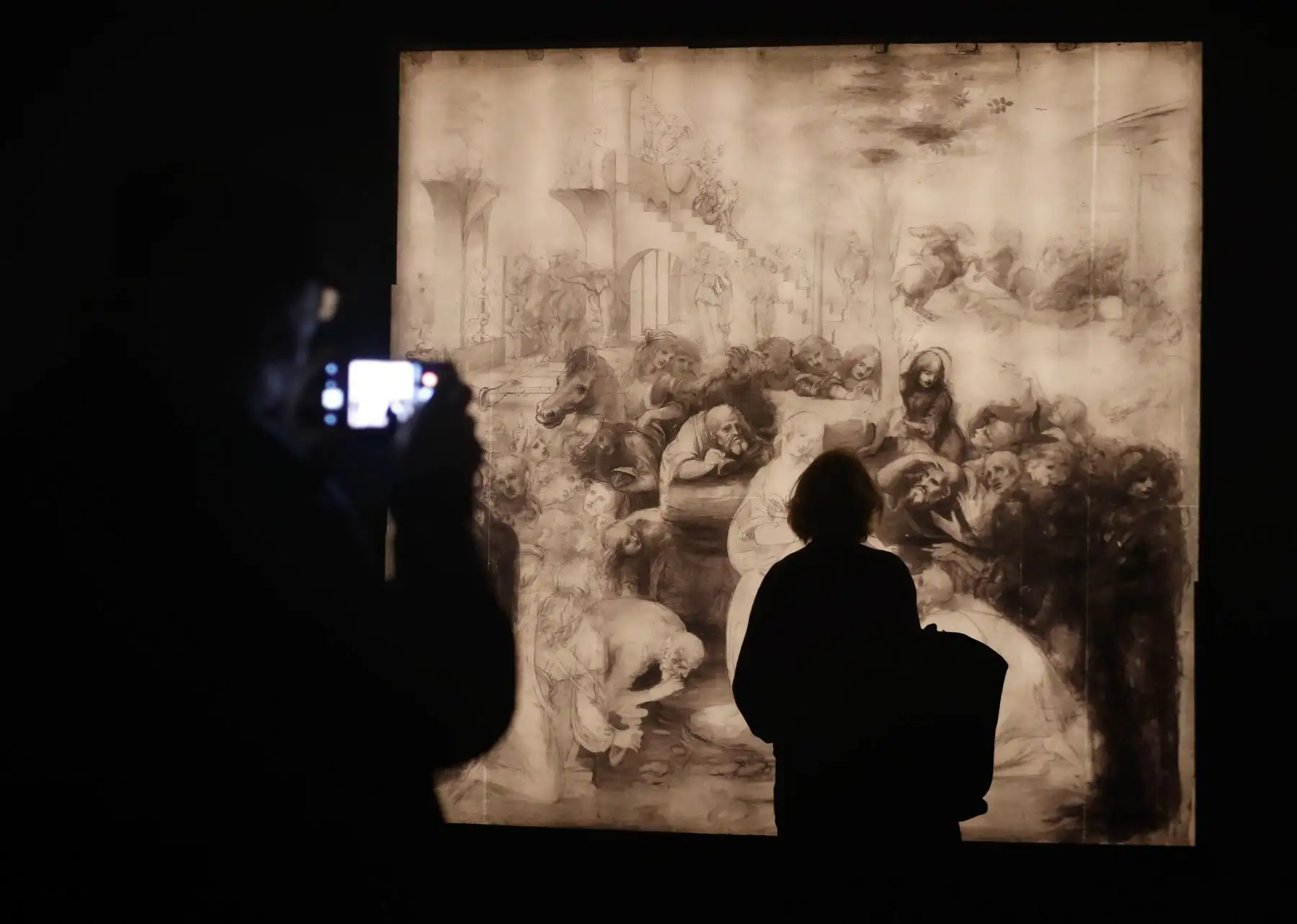 Una persona mira una reflectografía infrarroja de "La adoración de los magos" de Leonardo da Vinci durante la inauguración de la exposición "Leonardo da Vinci", en el museo del Louvre en París. Foto: AFP
