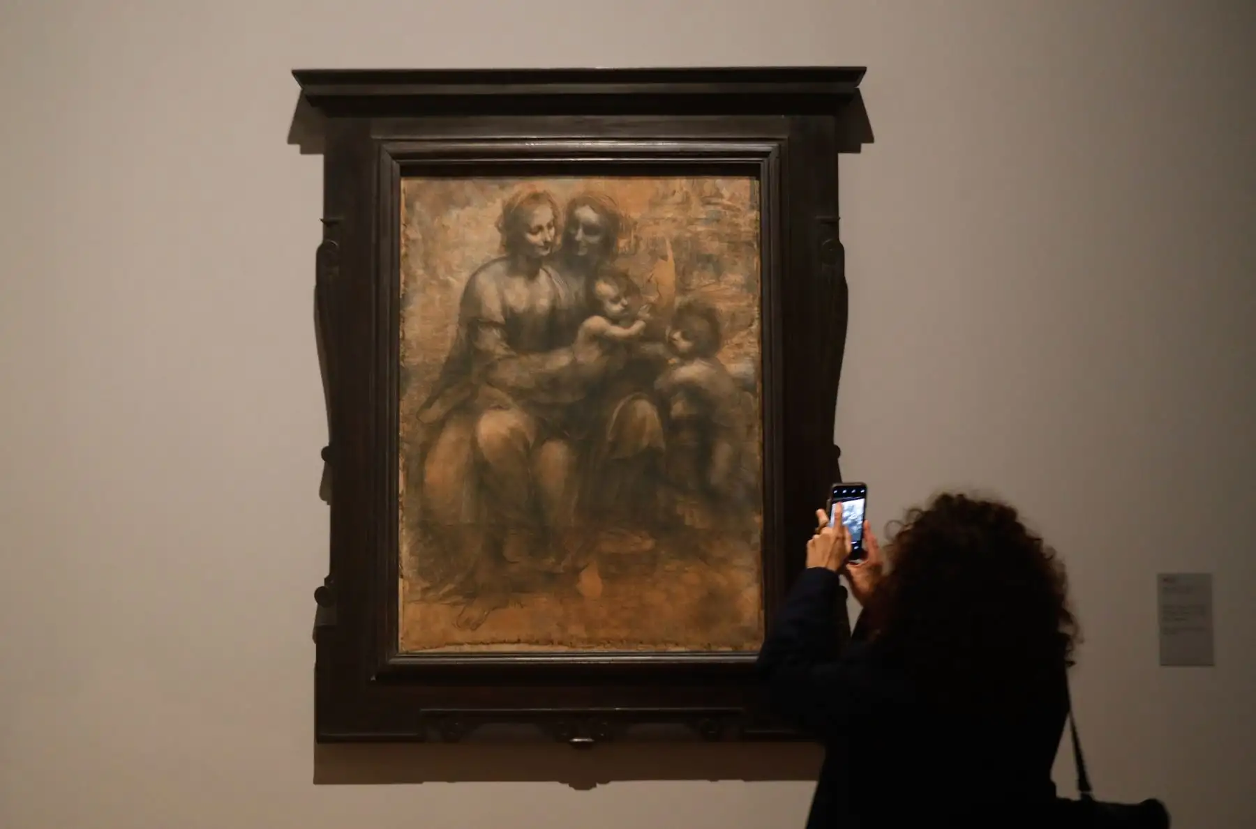 Una mujer mira un dibujo de "La Virgen, el Niño Jesús con Santa Ana y San Juan Bautista" de Leonardo da Vinci. Foto: AFP