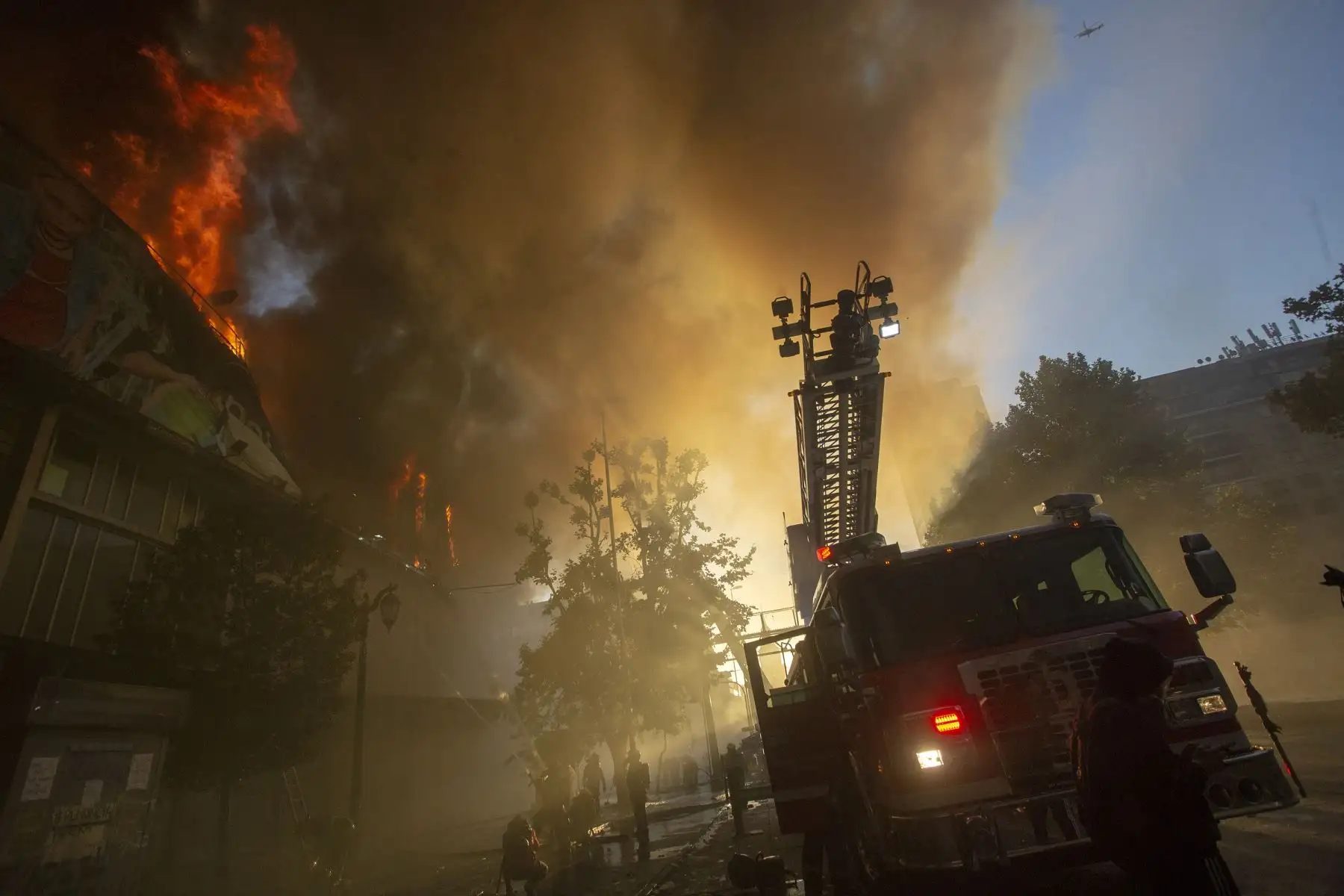 Los bomberos combaten un incendio en un edificio en Santiago momentos después de manifestaciones y protestas callejeras que han dejado al menos 20 personas muertas.Foto:AFP