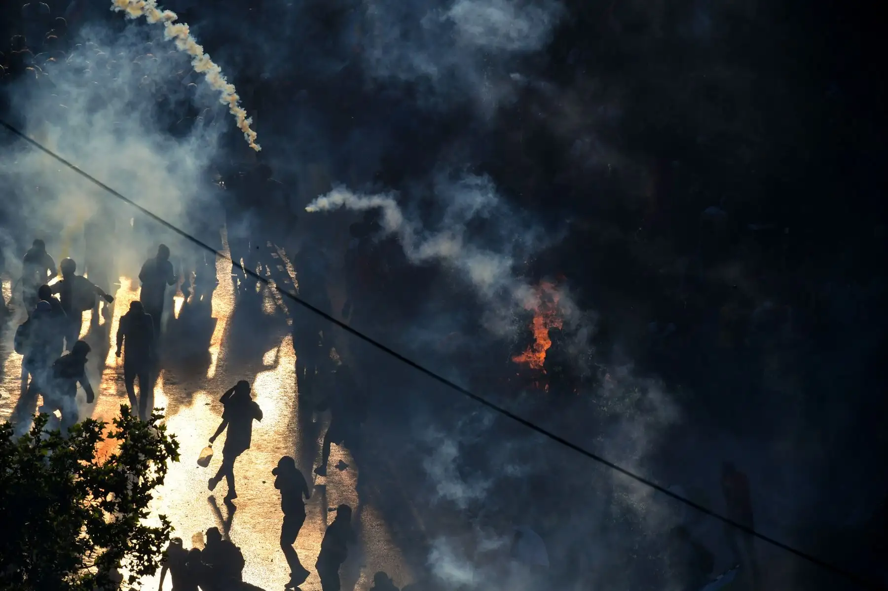 Los manifestantes son vistos a través del humo durante una manifestación en Santiago, quienes luchan por encontrar una respuesta a más de una semana de protestas callejeras que han dejado al menos 20 personas muerto. Foto:AFP