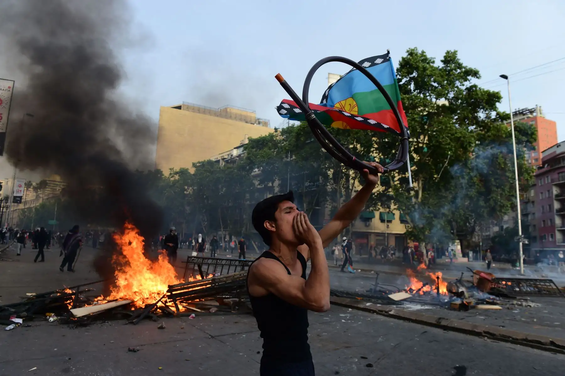 Un manifestante con una bandera indígena mapuche grita consignas en una barricada durante una protesta contra las políticas económicas del gobierno en los alrededores del palacio presidencial de La Moneda en Santiago.Foto:AFP