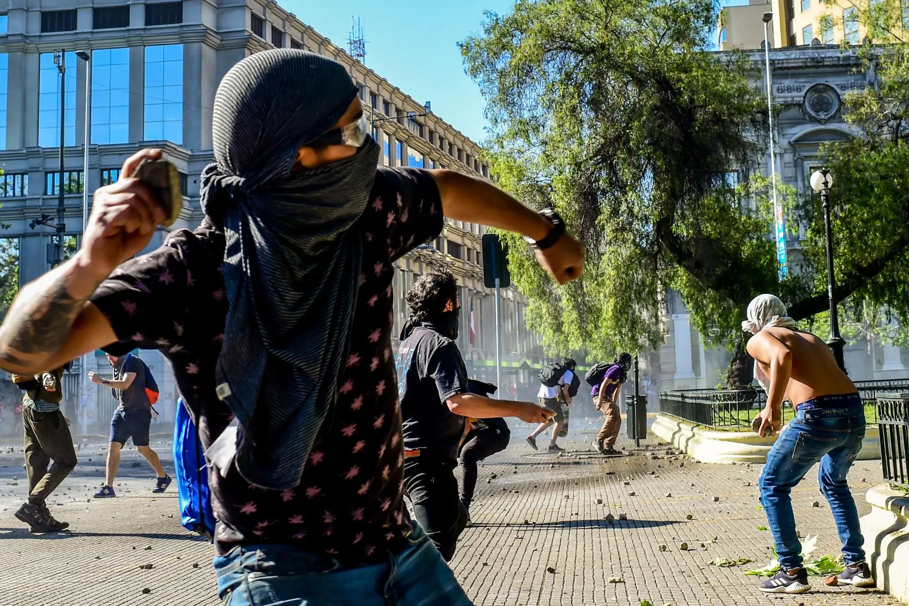 Los manifestantes arrojan piedras durante enfrentamientos con la policía frente al palacio presidencial de La Moneda.Mientras luchan por encontrar una respuesta a más de una semana de protestas callejeras que han dejado al menos 20 personas muertas.Foto:AFP