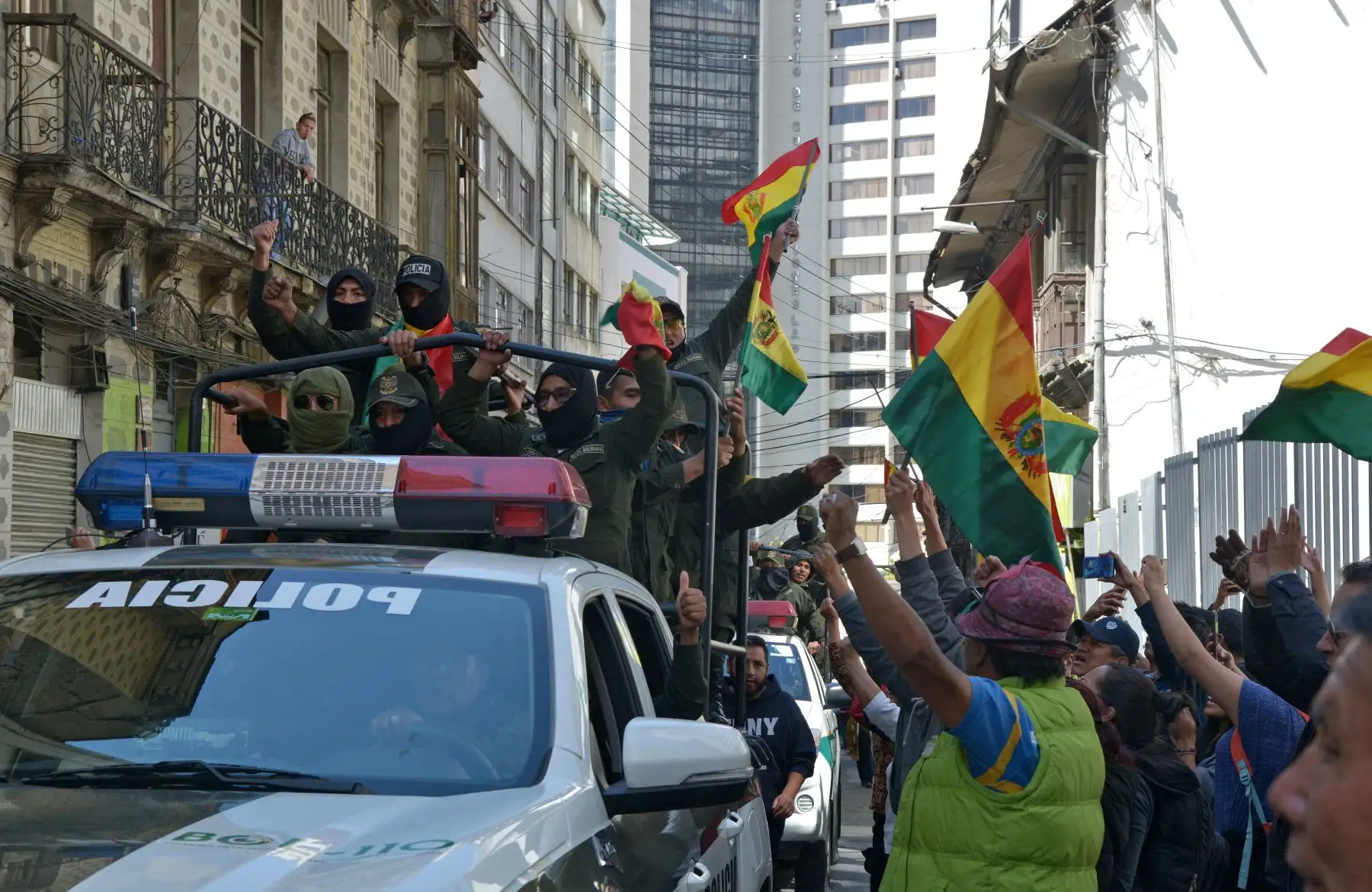 Los oficiales de la Unidad Táctica de Operaciones Especiales de la Policía (UTOP) que exhiben banderas bolivianas se dirigen a su cuartel general en la Plaza de Armas en La Paz. 
Después de anunciar que se unirían a una rebelión contra el presidente Evo Morales lanzada en la víspera por otras unidades.
Foto: AFP