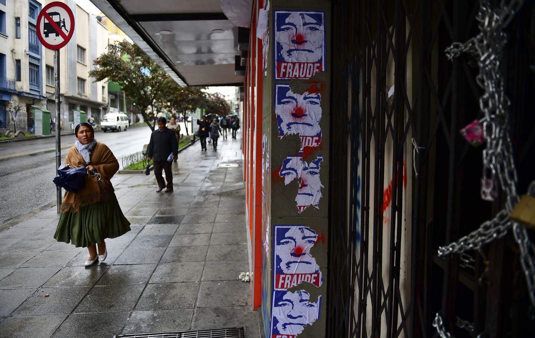 Una mujer camina junto a la pared con carteles del ex presidente boliviano Evo Morales representado como un payaso en La Paz. Foto: AFP