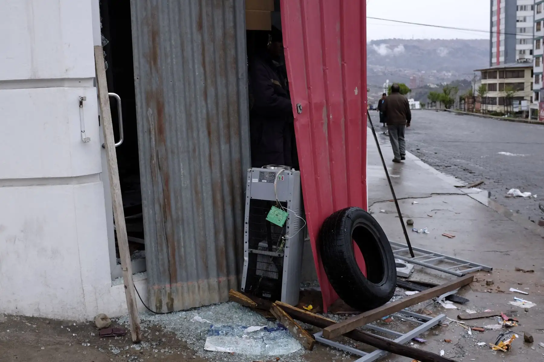 Un hombre camina cerca a una tienda cuya puerta se rompió durante las protestas de los partidarios del ex presidente boliviano Evo Morales después de su renuncia . 
Foto: AFP