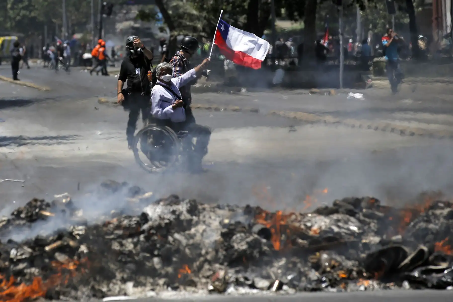 Un hombre en silla de ruedas ondea la bandera nacional chilena junto a una hoguera durante una protesta contra el gobierno de Sebastián Piñera en Santiago de Chile.
Foto: AFP