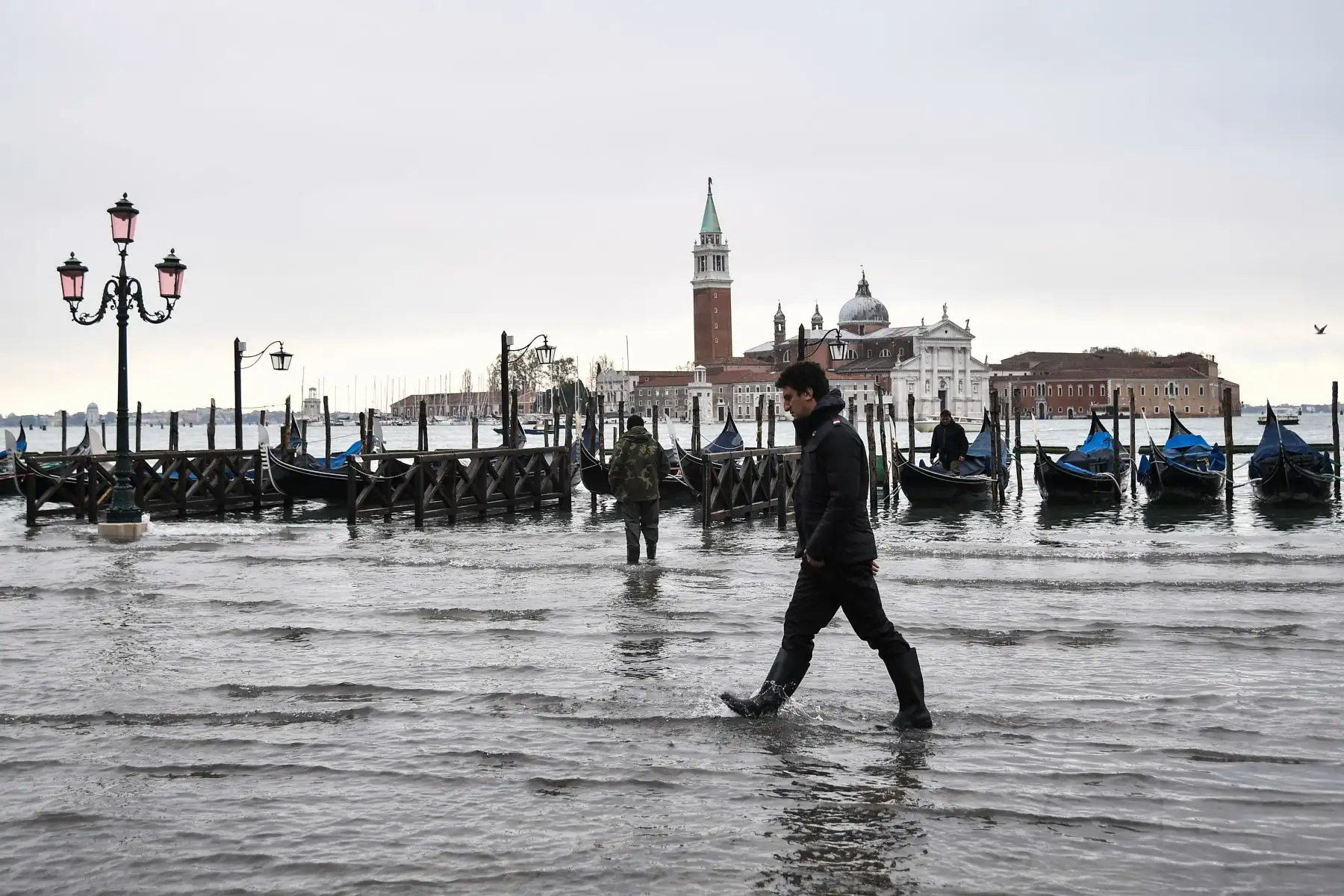 Un hombre camina por el terraplén inundado de Riva degli Schiavoni con la basílica de San Giorgio Maggiore en el fondo, después de un excepcional nivel de agua durante la marea alta en Venecia.
Foto: AFP