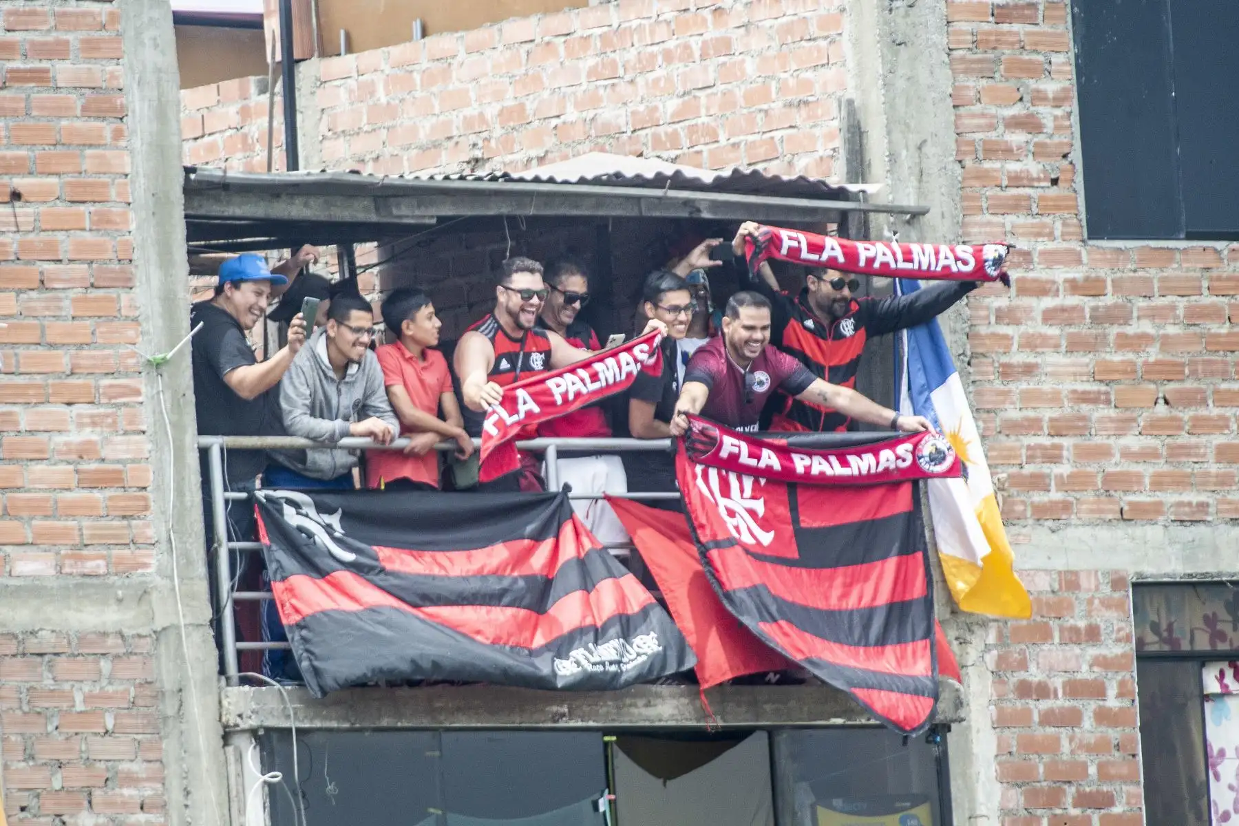 Hinchas del Flamengo de Brasil miran una sesión de entrenamiento desde una casa vecina en Lima. Foto: AFP