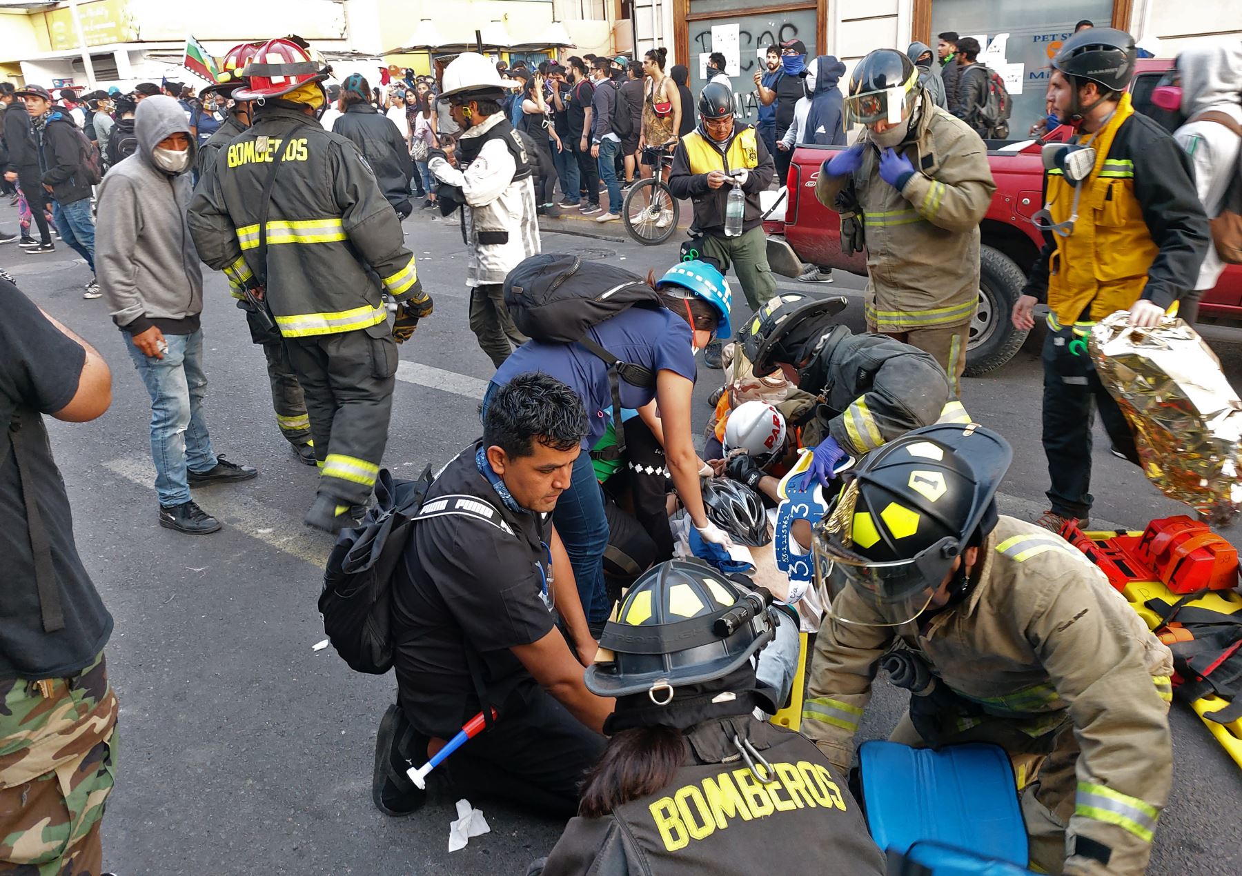 Bomberos ayudan a heridos después de que un automóvil atropelló a personas que protestaban contra el gobierno de Sebastián Piñera en Antofagasta, Chile. Foto: AFP