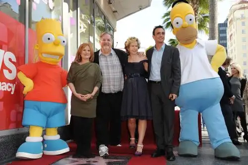 Bart y Homero Simpson, personajes de la serie Los Simpson, posan con su creador, Matt Groening (con lentes y camisa a cuadros). Foto: AFP.