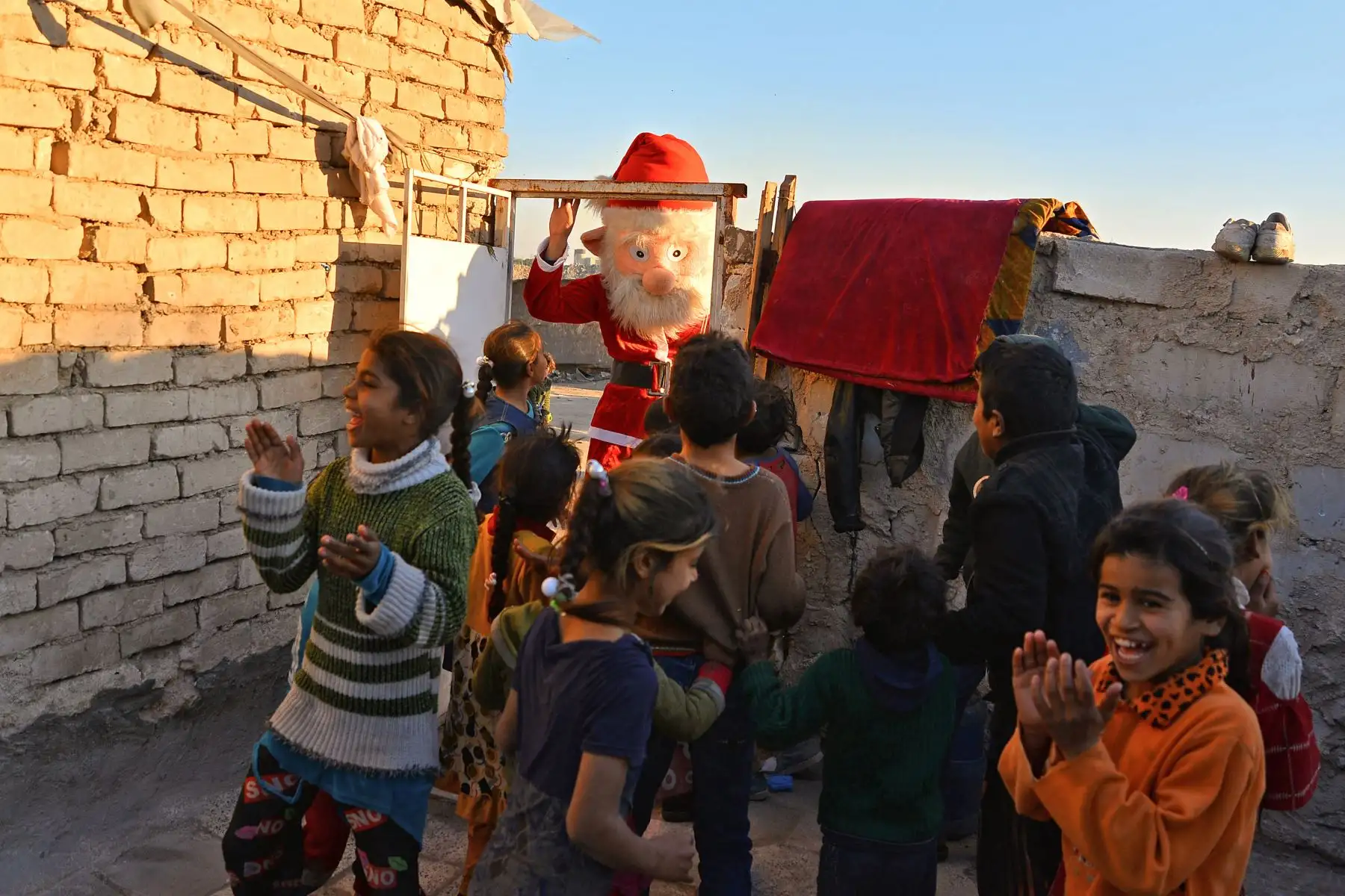 Niños iraquíes aplauden cuando un hombre vestido como Santa Claus llega para distribuir regalos en Najaf. Foto: AFP