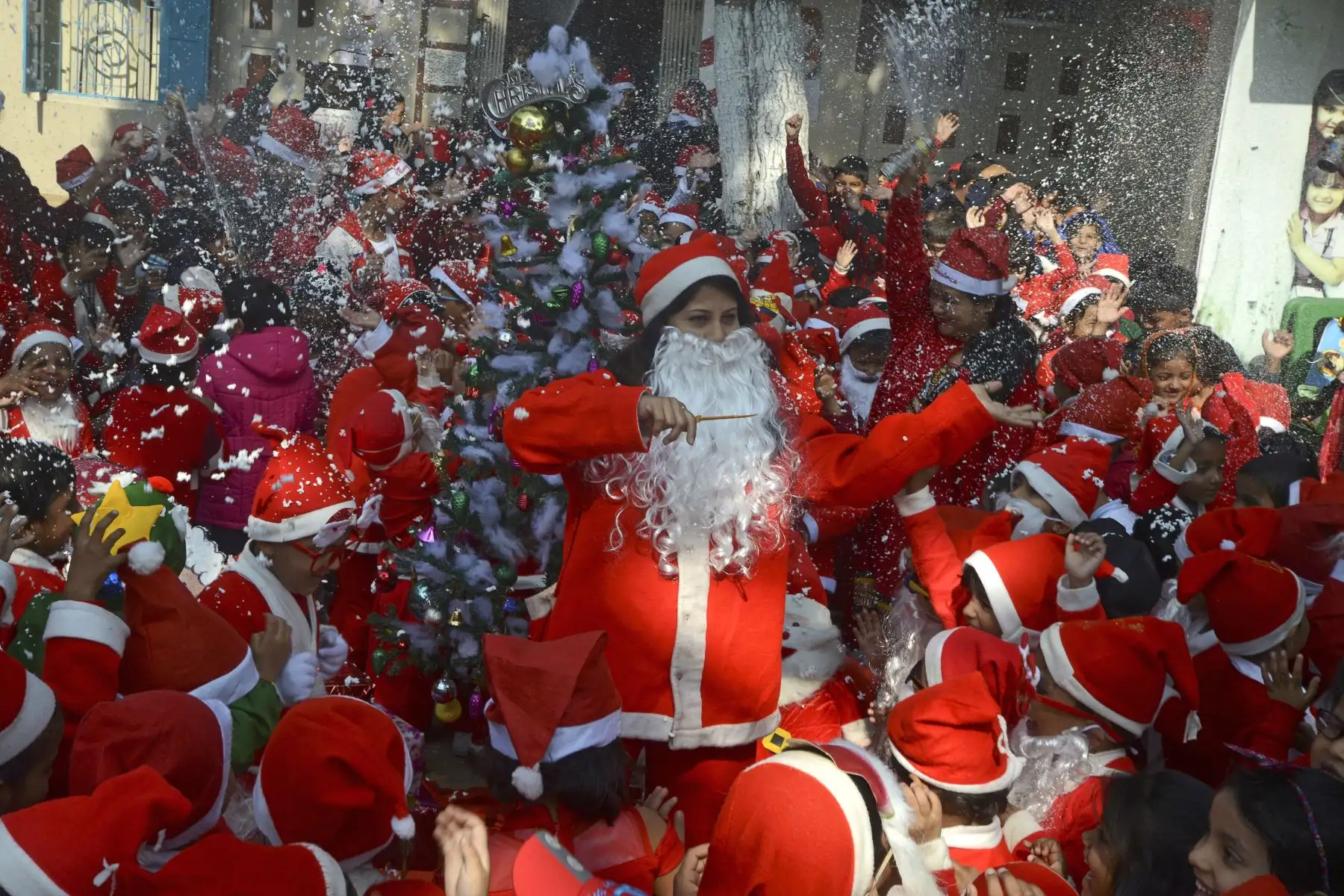 Niños de la escuela junto con maestros disfrazados de Santa Claus participan en un evento navideño en la India. Foto: AFP