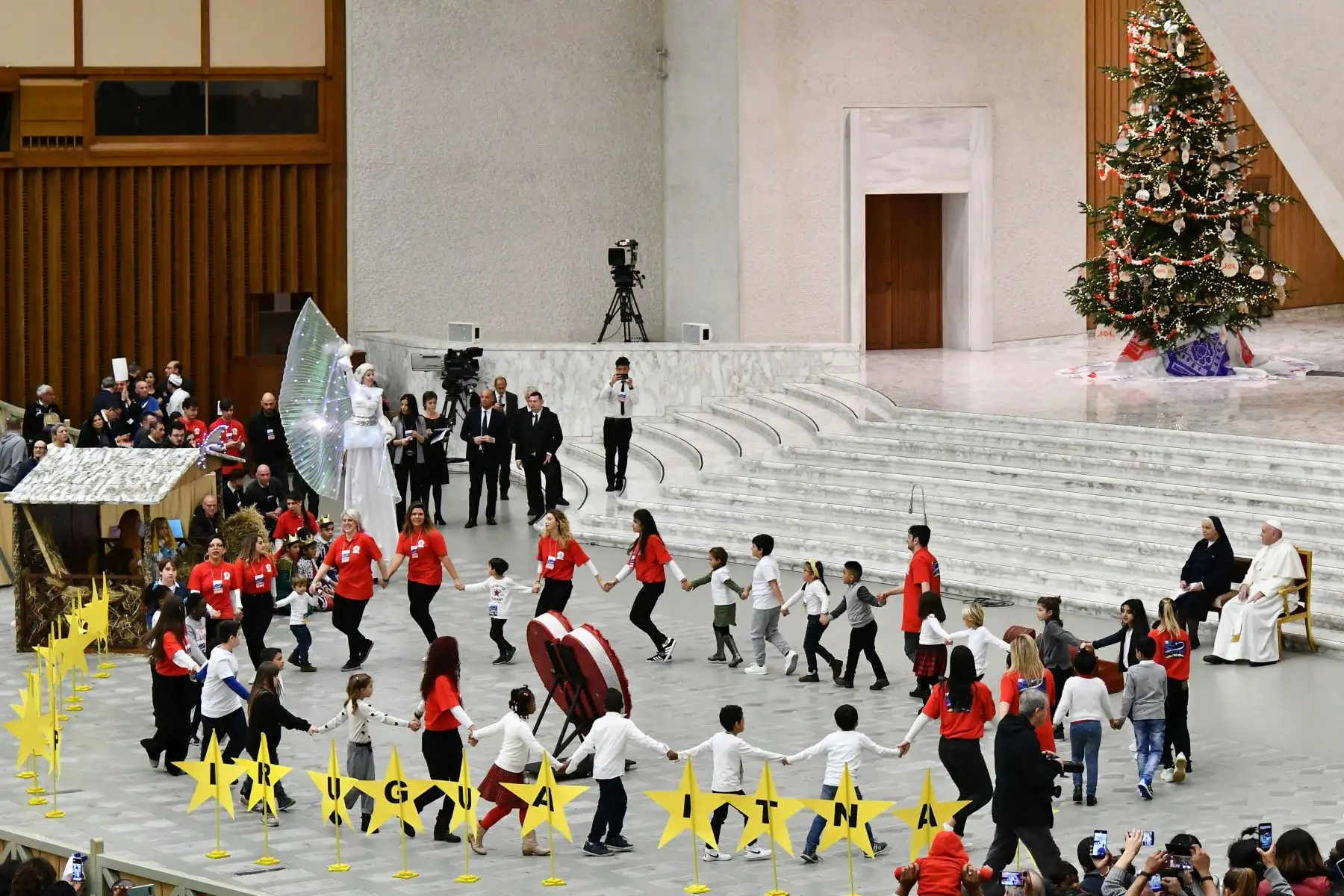 El Papa Francisco y Suor Antonietta Collacchi, director del dispensario de Santa Marta miran a los niños bailando en círculo alrededor de letras que leen "Best Wishes" durante una audiencia para niños y familias del dispensario de Santa Marta en el Vaticano.
Foto: AFP