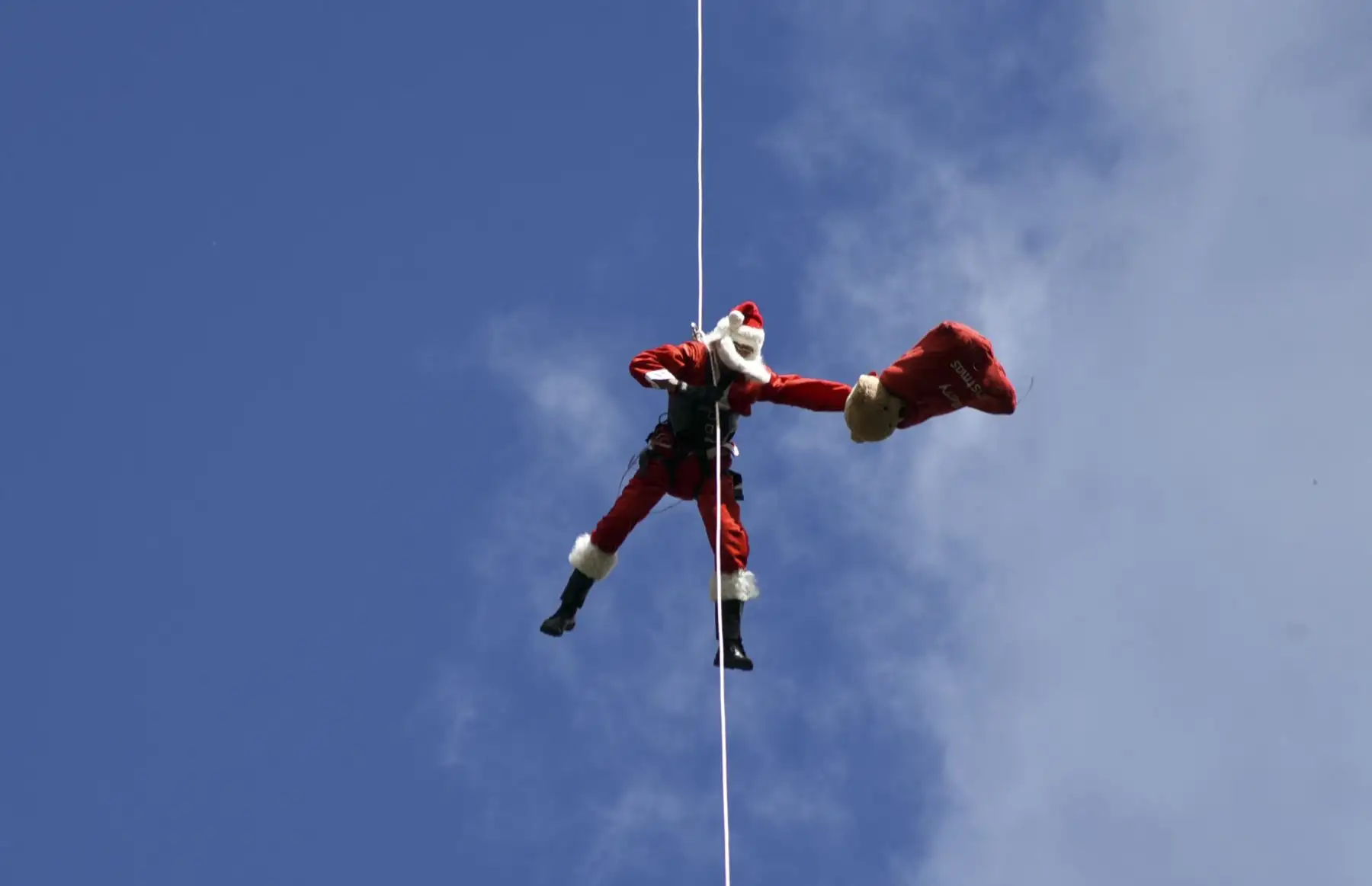 El bombero municipal guatemalteco Héctor Chacón, vestido como Santa Claus, baja por un cable desde un puente para entregar regalos a los niños en la Ciudad de Guatemala.
Foto: AFP