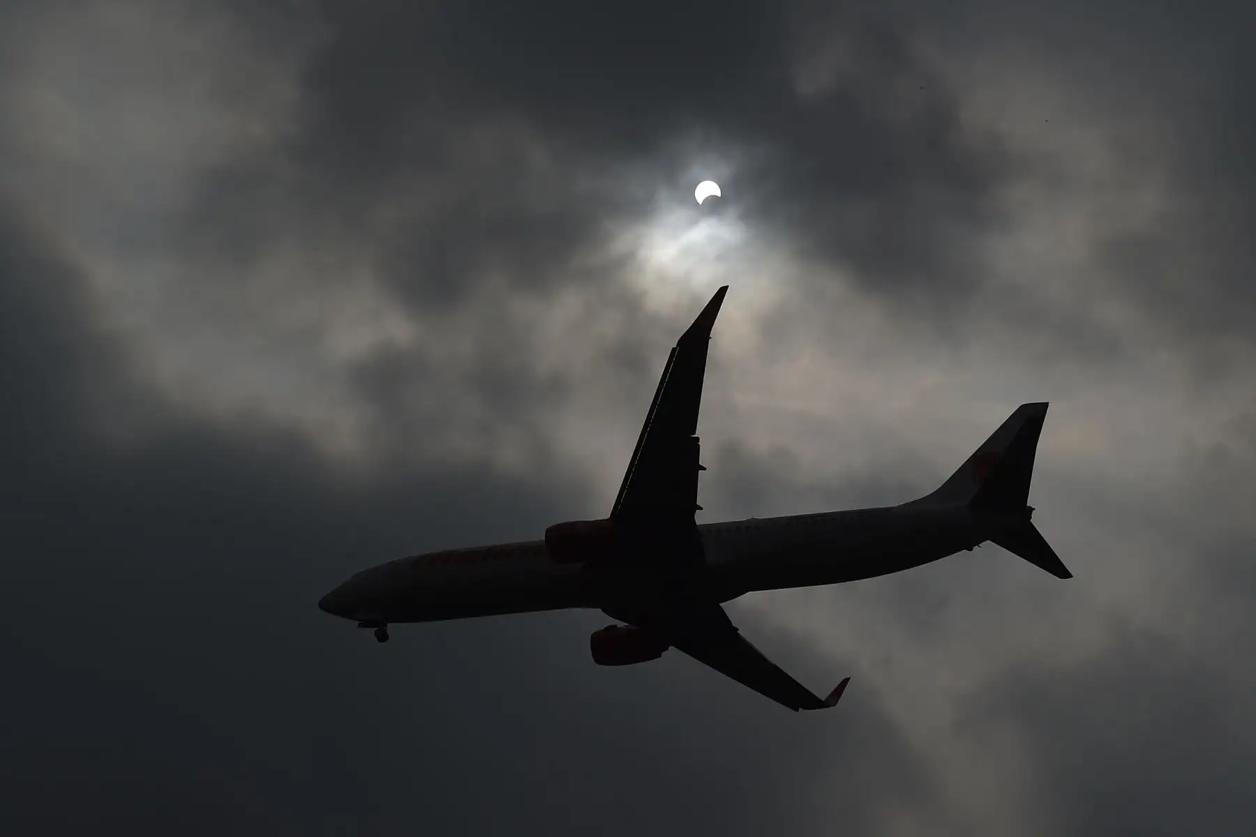Un avión pasa cuando la luna se mueve frente al sol en un eclipse solar de "anillo de fuego" visto desde Hanoi el 26 de diciembre de 2019. Foto: AFP