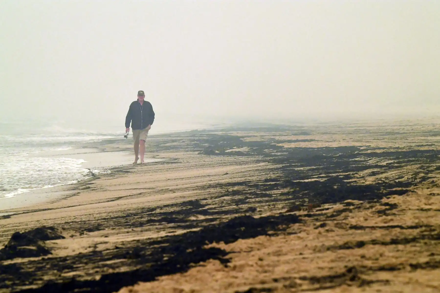 El residente local Dave Iredale pasa las cenizas de los incendios forestales arrasados ​​en una playa en Merimbula, en el estado australiano de Nueva Gales del Sur.
Foto: AFP