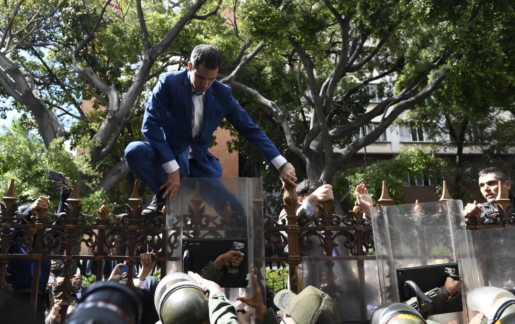 El líder de la oposición venezolana y autoproclamado presidente en funciones, Juan Guaido, recibe ayuda para subir una barandilla en un intento de llegar al edificio de la Asamblea Nacional en Caracas.
Foto: AFP