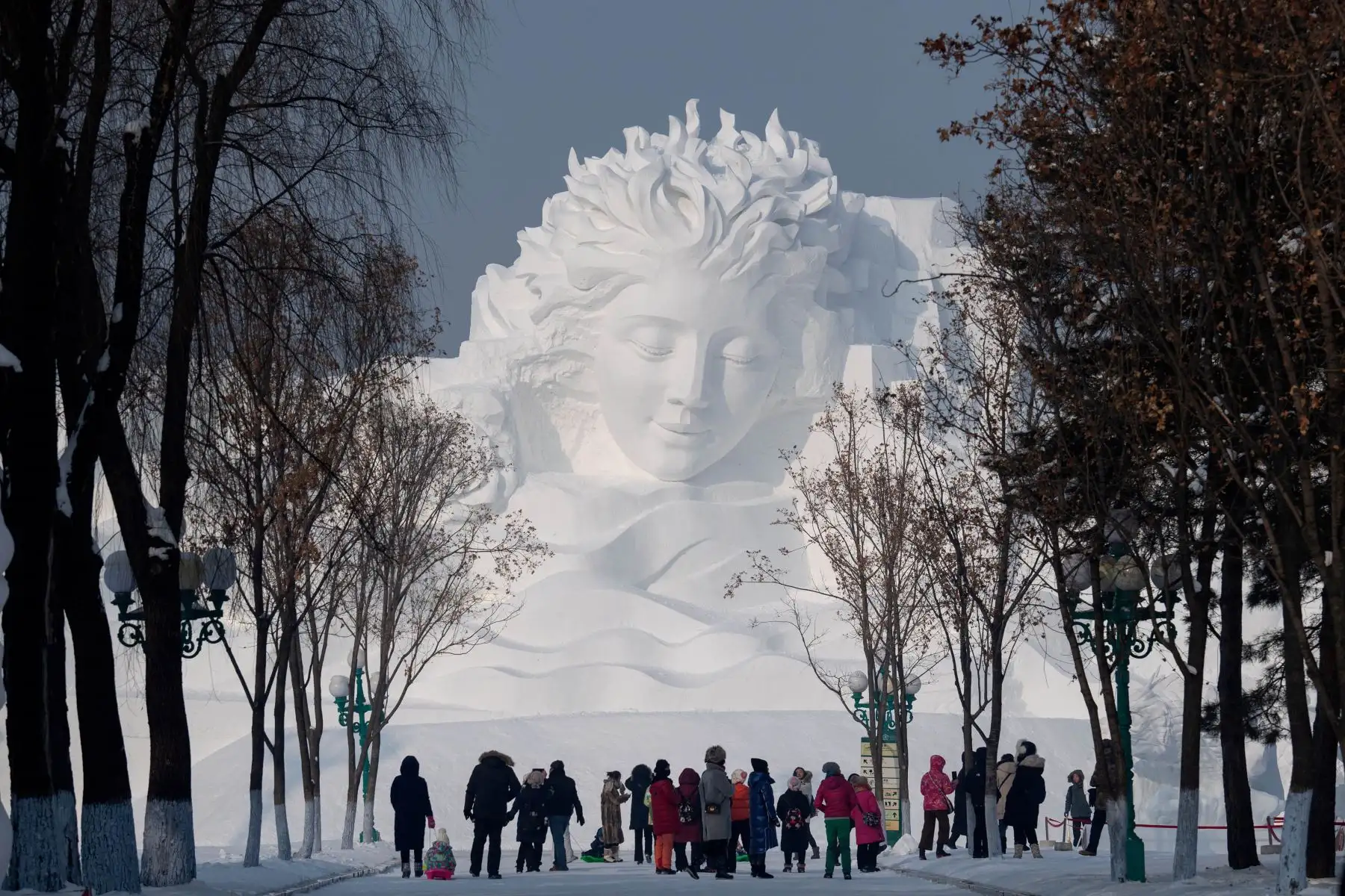 Los turistas caminan frente a una escultura de hielo durante el Festival Internacional de Hielo y Nieve de Harbin en China. Foto: AFP