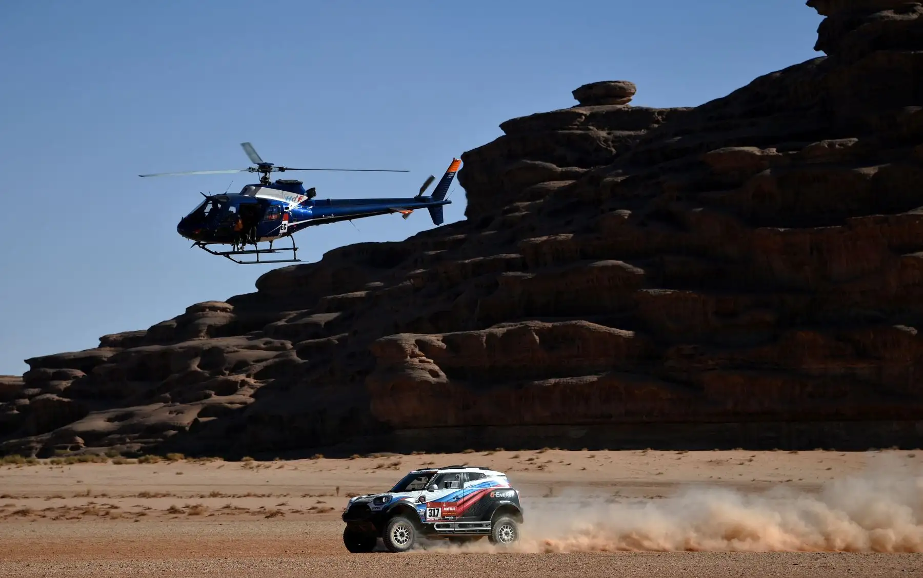 Un helicóptero vuela mientras el piloto ruso Vladimir Vasilyev y el copiloto Vitaly Yevtyekhov de Ucrania manejan su Mini durante la Etapa 3 del Dakar 2020 alrededor de Neom, Arabia Saudita.
Foto: AFP