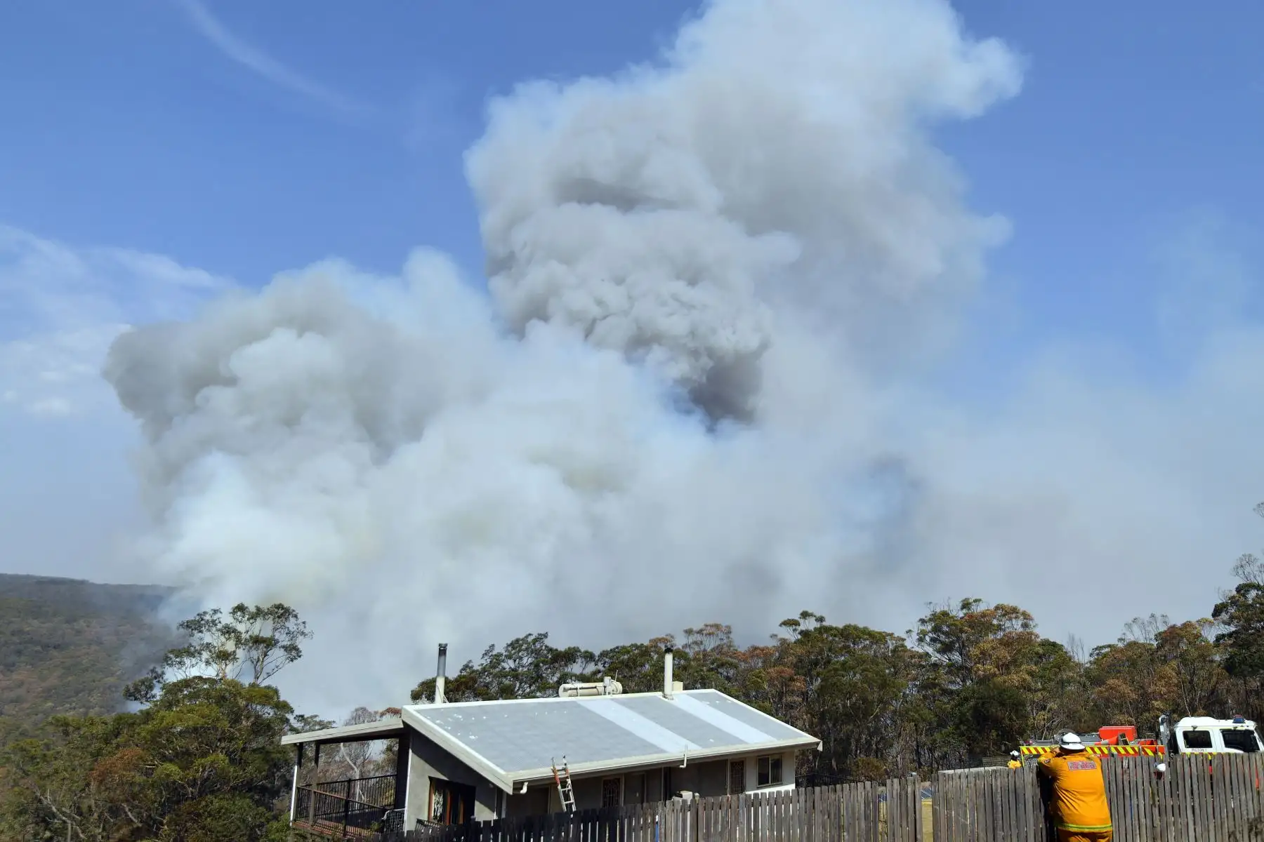 Bomberos trabajan mientras el humo se eleva de un incendio forestal en Penrose, en el estado australiano de Nueva Gales del Sur. Foto: AFP