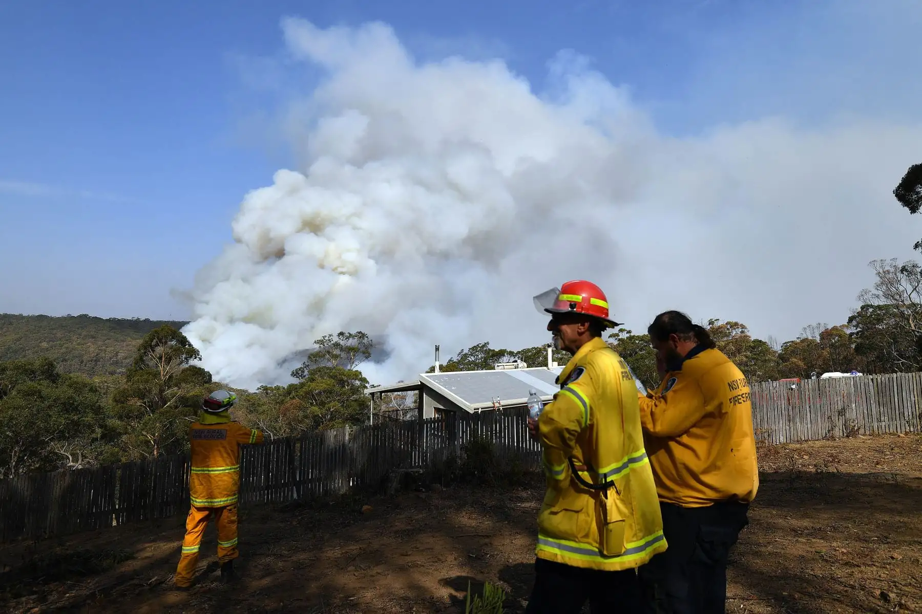 Bomberos trabajan mientras el humo se eleva de un incendio forestal en Penrose, en el estado australiano de Nueva Gales del Sur. Foto: AFP