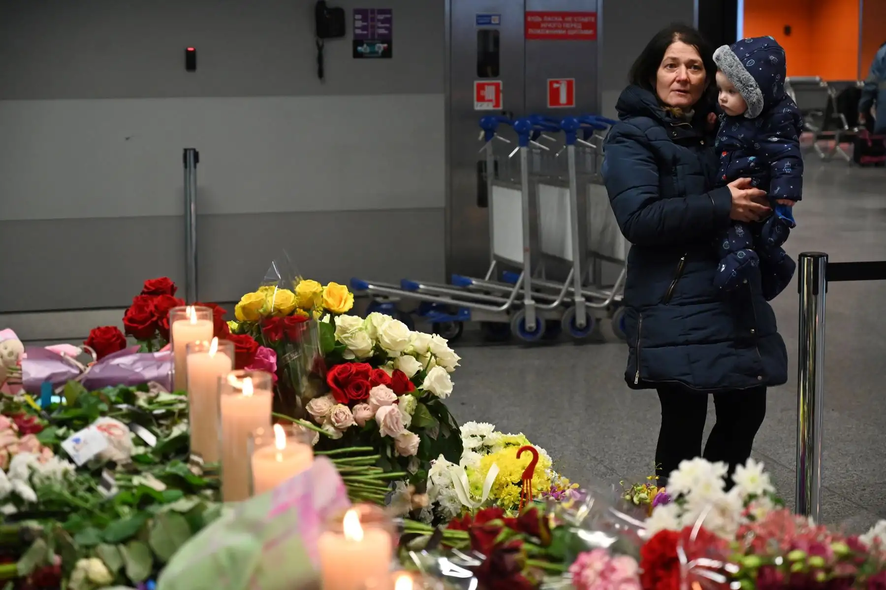 Una mujer reacciona mientras sostiene a un niño en el aeropuerto de Boryspil, en las afueras de Kiev, mientras rinde homenaje en un monumento improvisado para las víctimas del Boeing 737-800 de Ukraine International Airlines que se estrelló cerca de la capital iraní, Teherán. 
Foto: AFP