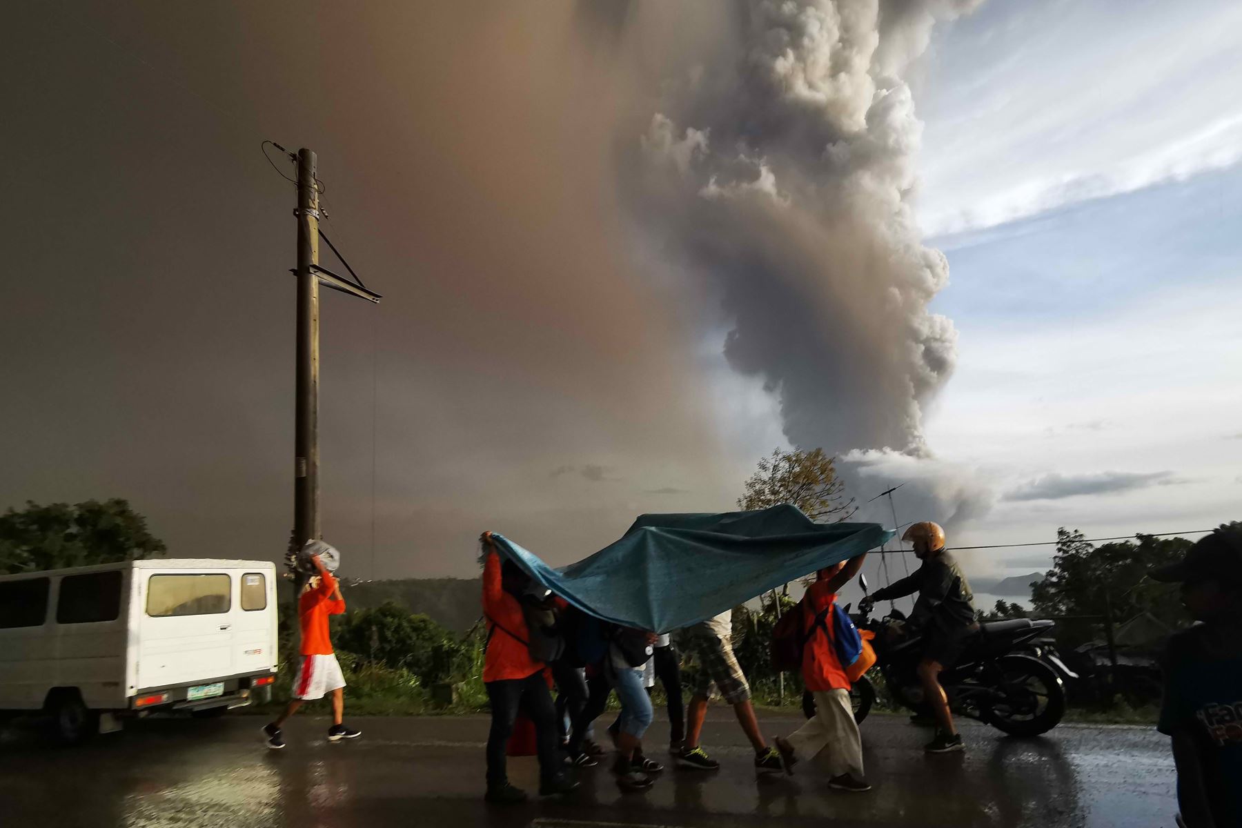 Las personas se refugian debajo de una gran sábana de plástico mientras una columna de cenizas arroja el volcán Taal en erupción sobre la ciudad de Tagaytay, Filipinas.
Foto: AFP
