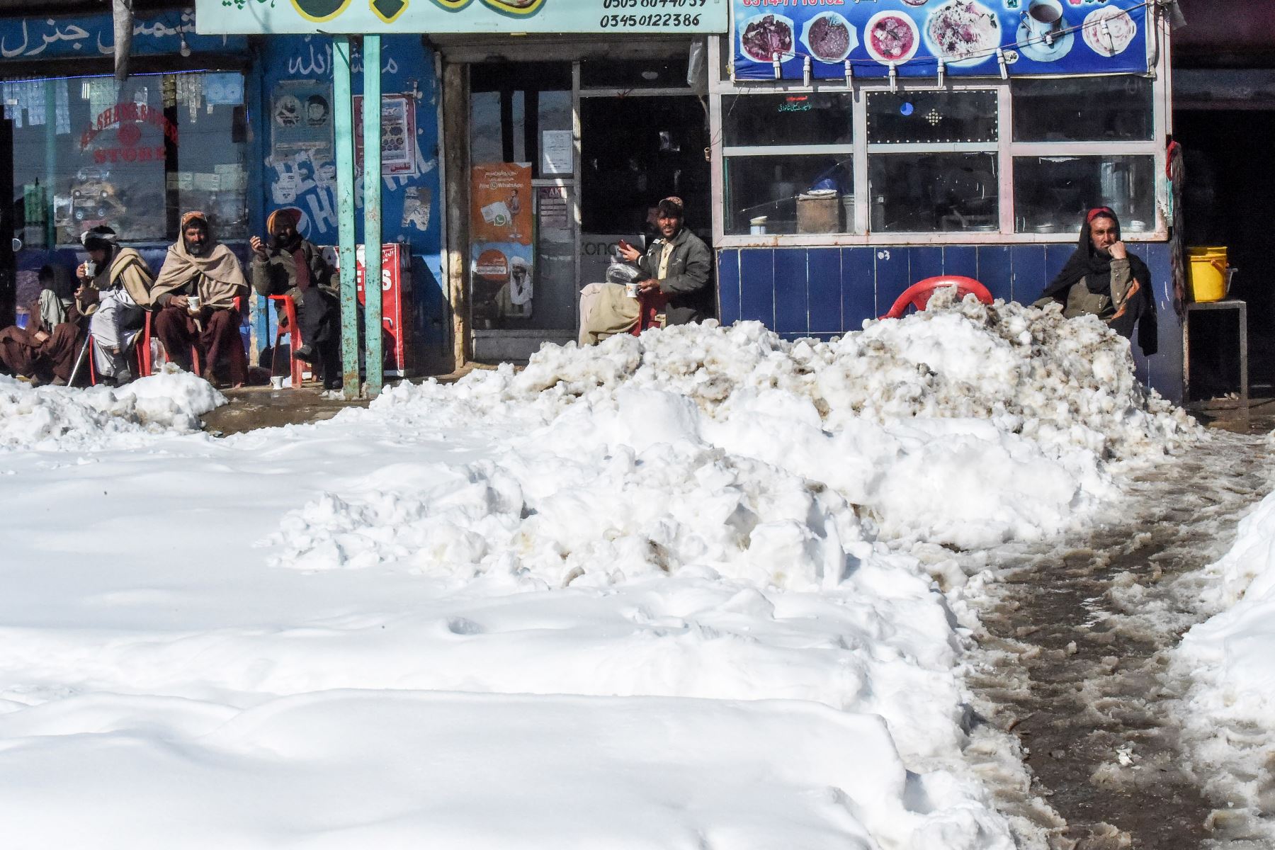 Los residentes locales se sientan en un hotel junto a la carretera después de las fuertes nevadas en el área de Khanozai. Foto: AFP