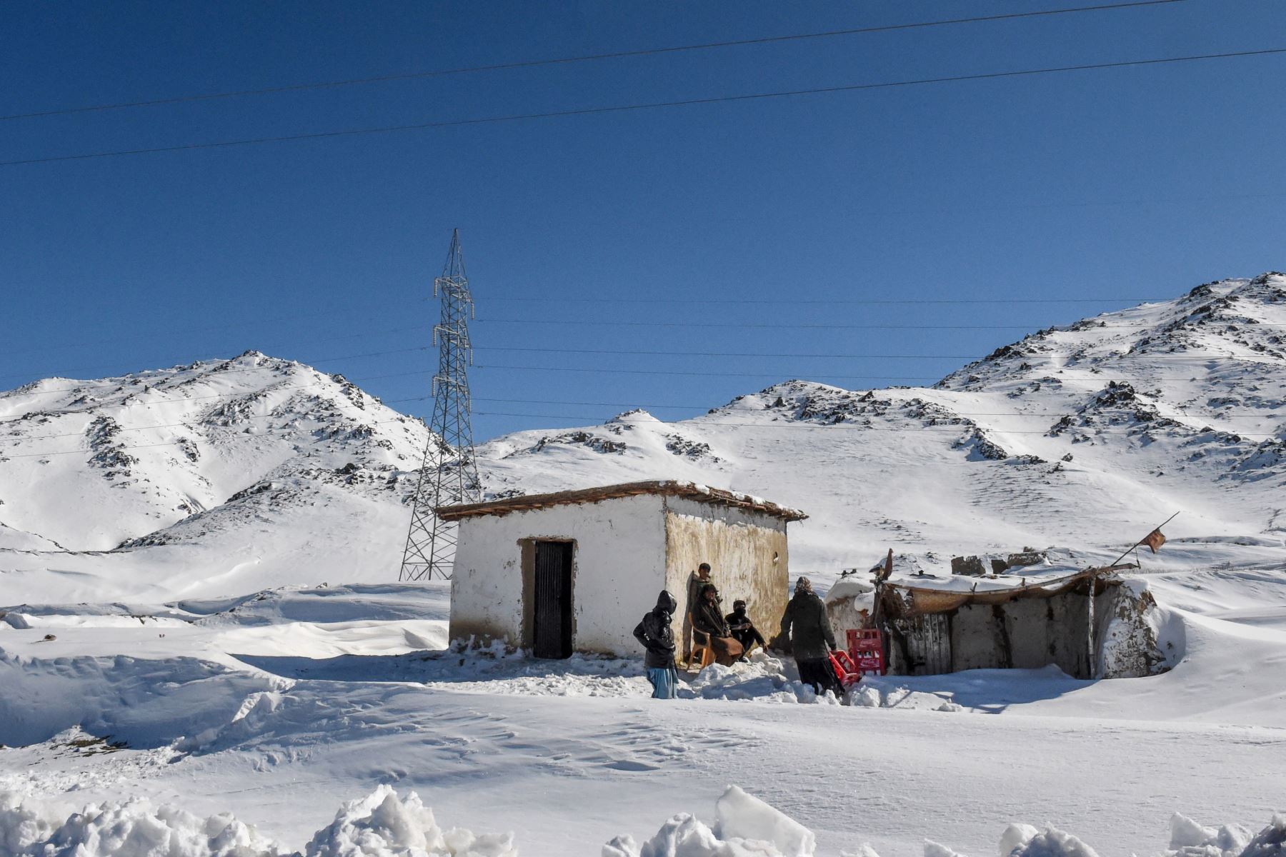 Trabajadores se sientan afuera de una tienda cerrada después de las fuertes nevadas en el área de Khanozai, a unos 75 kilómetros al noreste de la capital provincial, Quetta. Foto: AFP