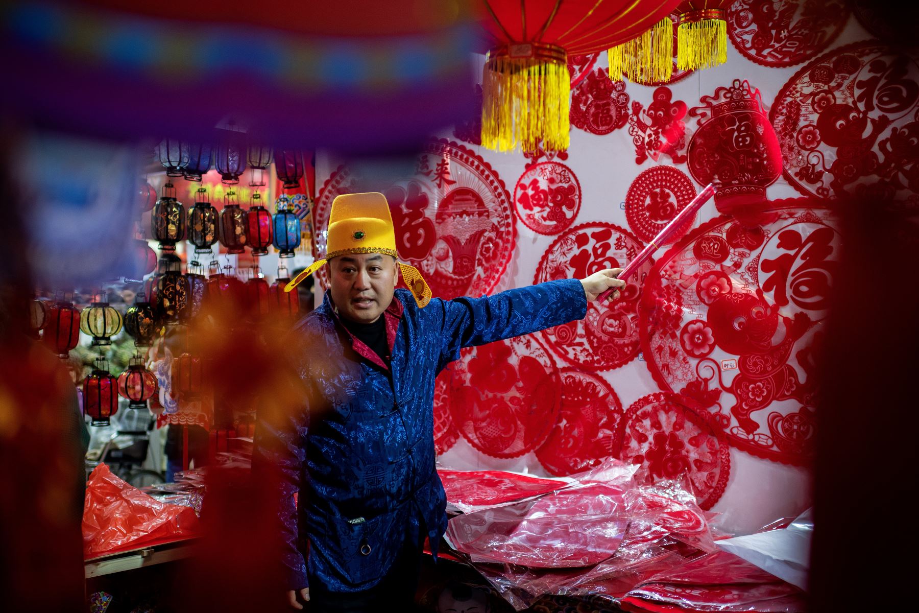 Un vendedor señala decoraciones festivas mientras habla con un cliente en su puesto en un mercado en Beijing, antes del Año Nuevo Lunar de la Rata.
Foto: AFP