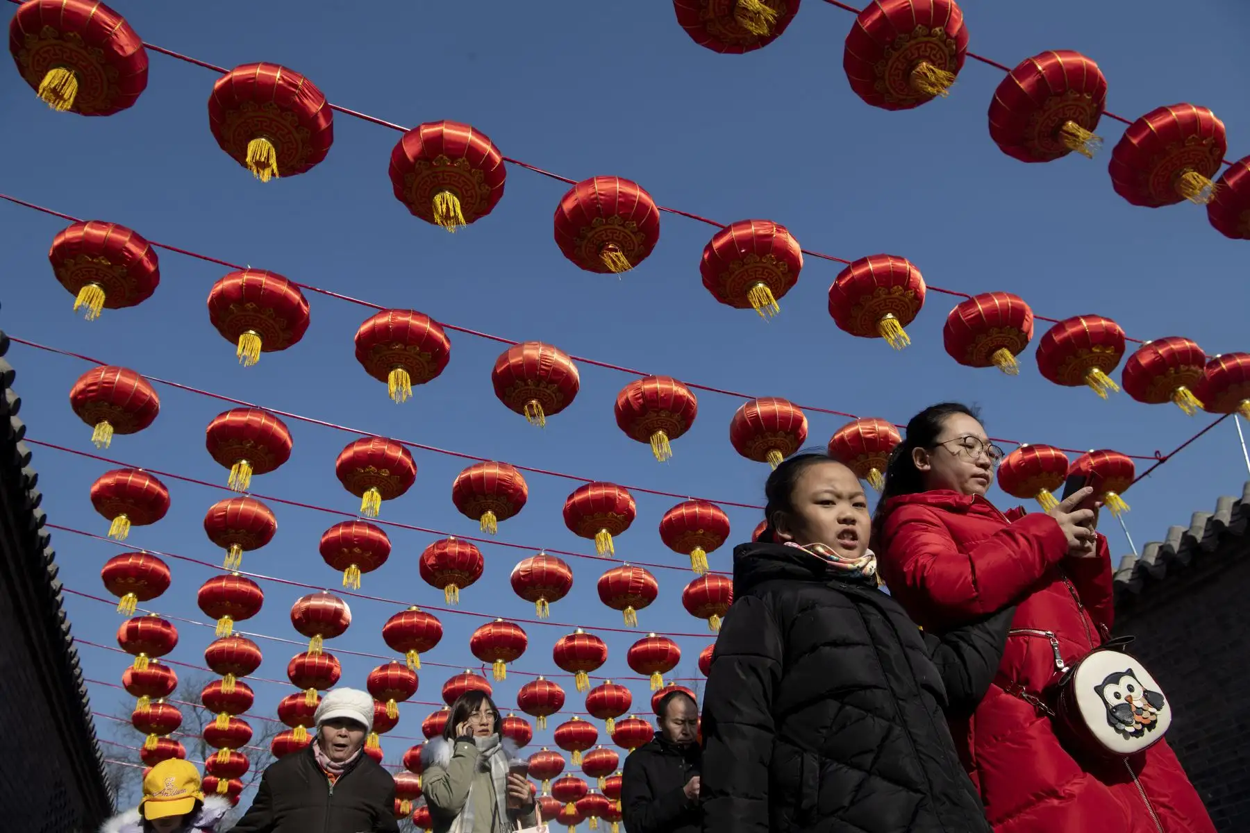 La gente camina bajo linternas chinas a lo largo de una calle en Beijing, antes del Año Nuevo Lunar de la Rata.
Foto: AFP