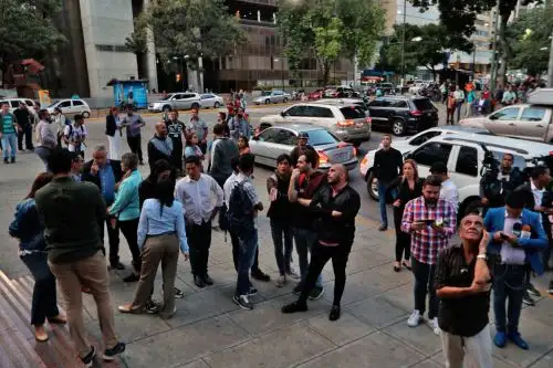 Simpatizantes de Juan Guaidó y diputados venezolanos aguardan en los alrededores del edificio donde fue allanada la oficina del líder opositor. Foto: EFE